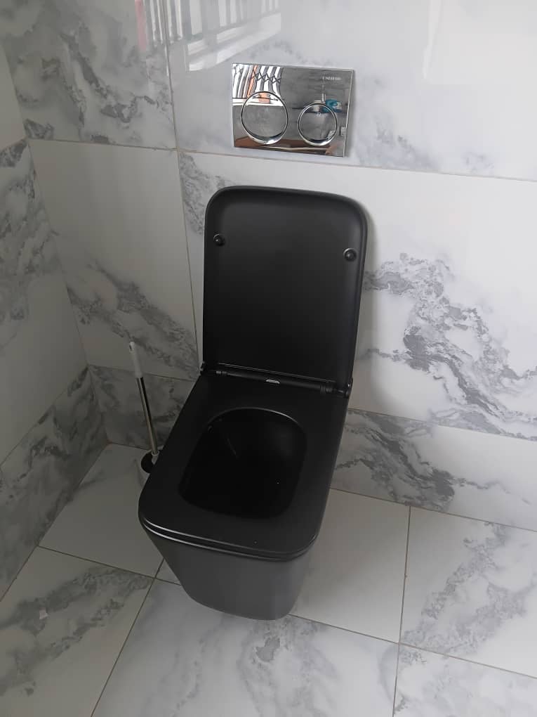 Bathroom tiling — black wall-hung toilet against marble-effect white wall and floor tiles