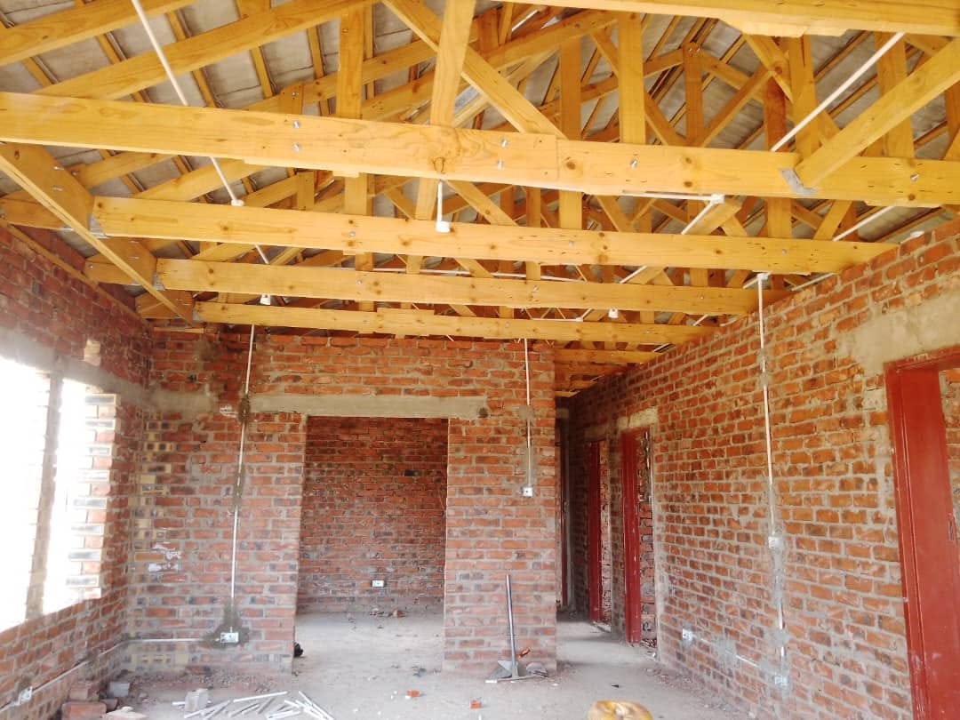 Structural & electrical — interior brick room with exposed wooden roof trusses and conduit drops
