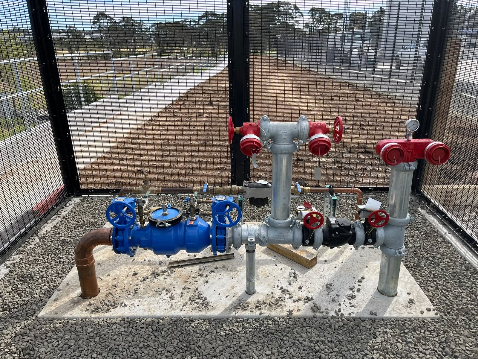 Backflow prevention and booster pump valve assembly in security cage
