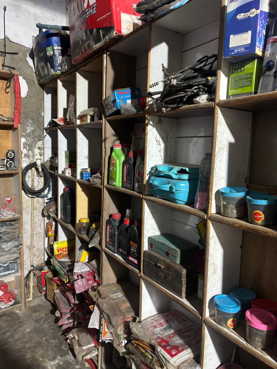 Motorcycle parts and engine oils arranged on workshop shelves