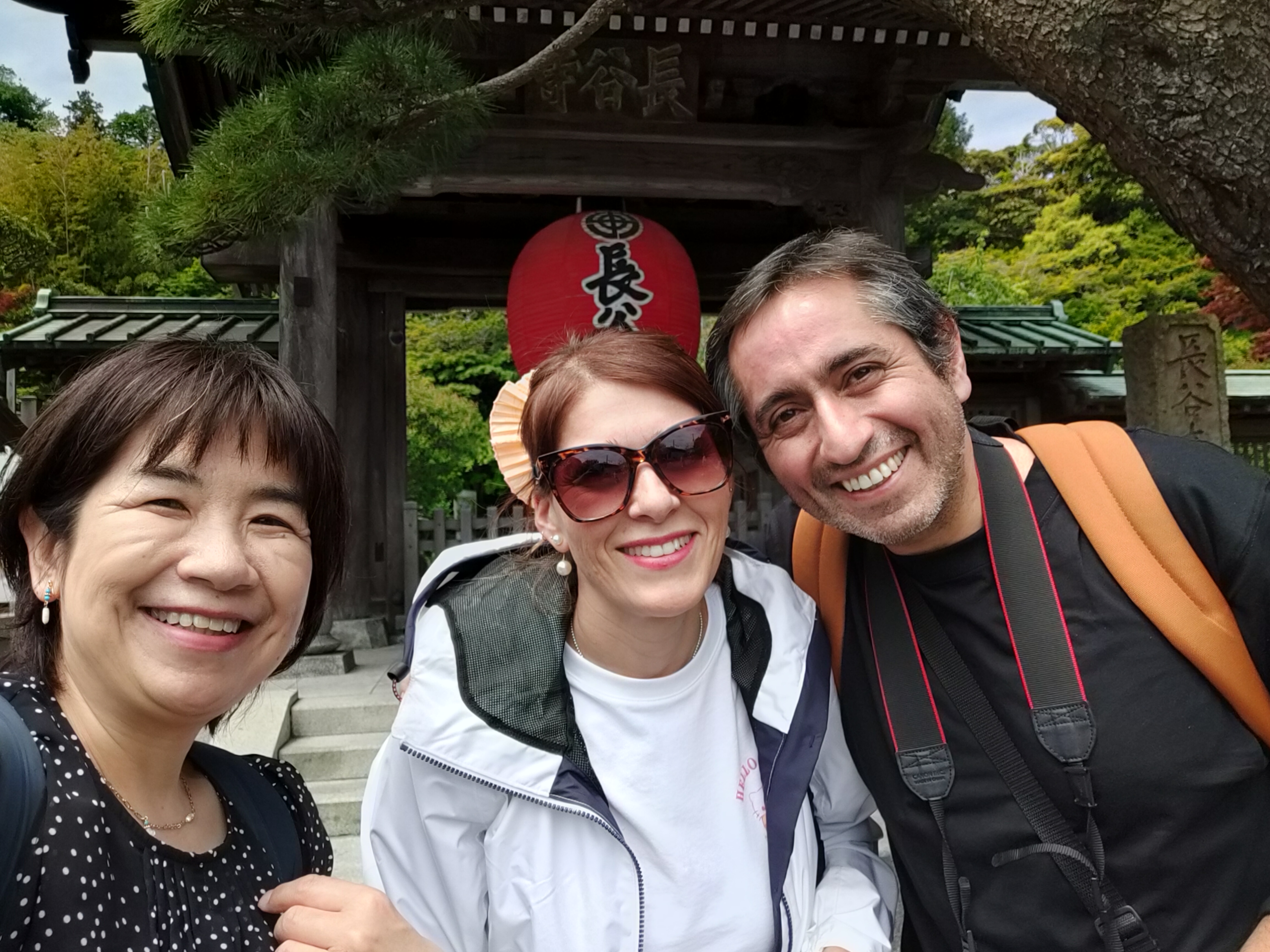 Bisco taking a selfie with tour guests at Hase-dera temple entrance with traditional red lantern