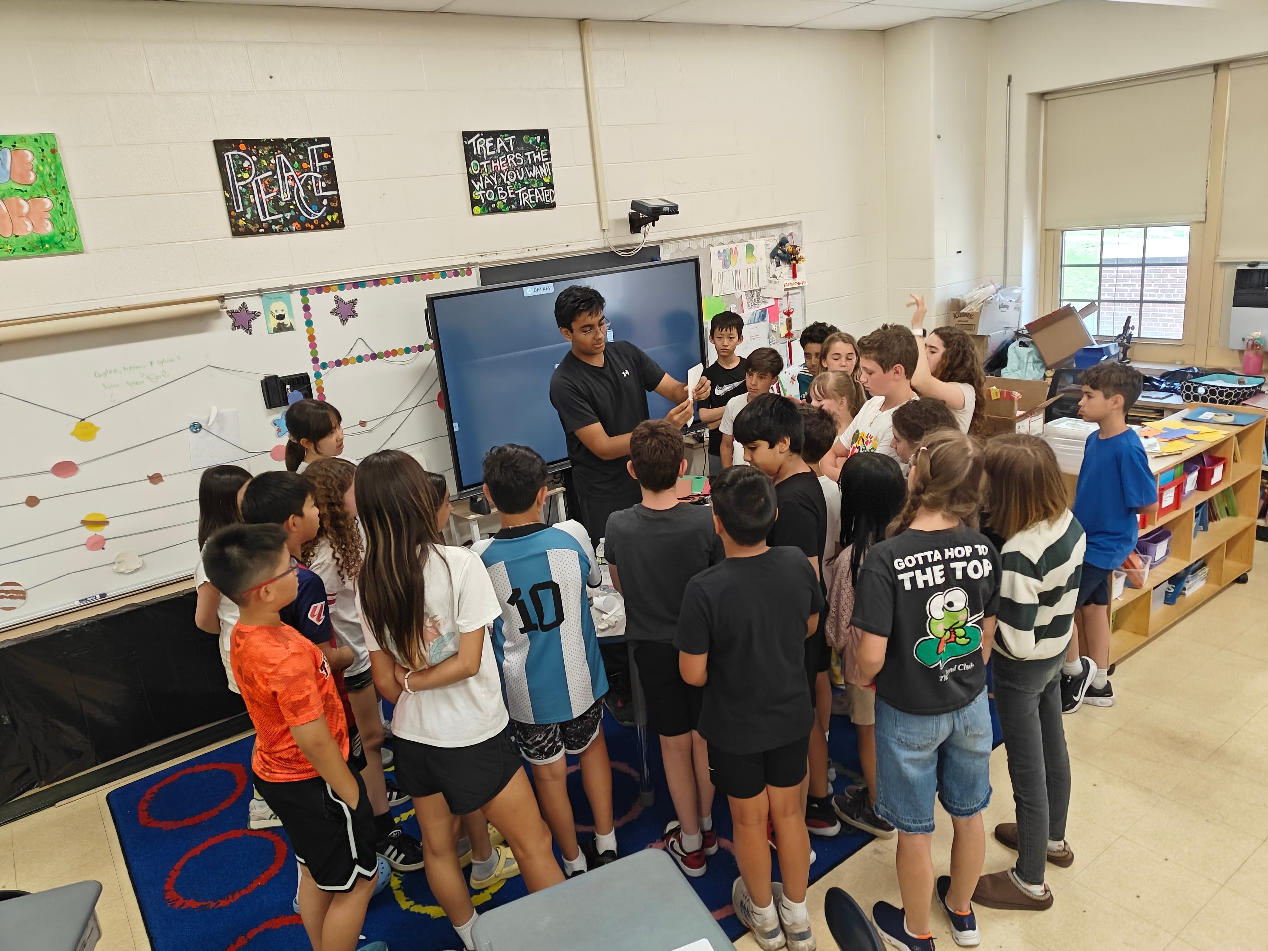 Elementary school students gathered around a presenter during a hands-on science session