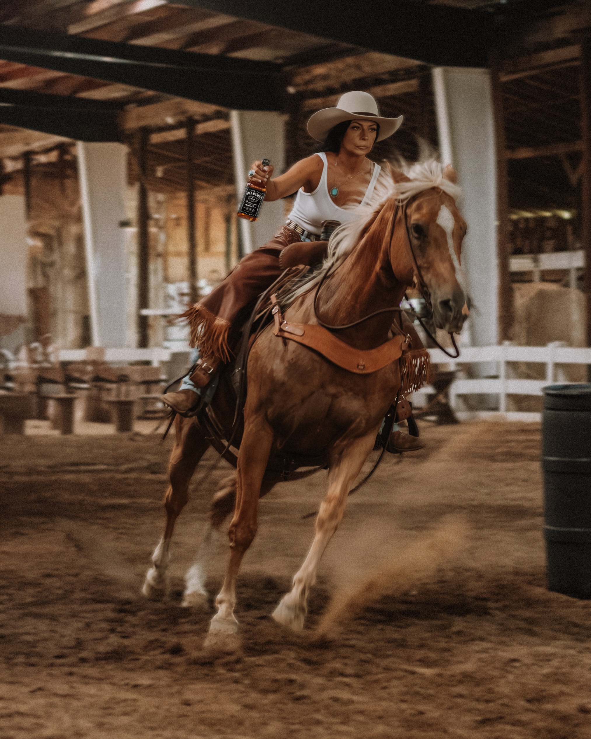 Cowgirl riding horse at full gallop holding Jack Daniel's bottle