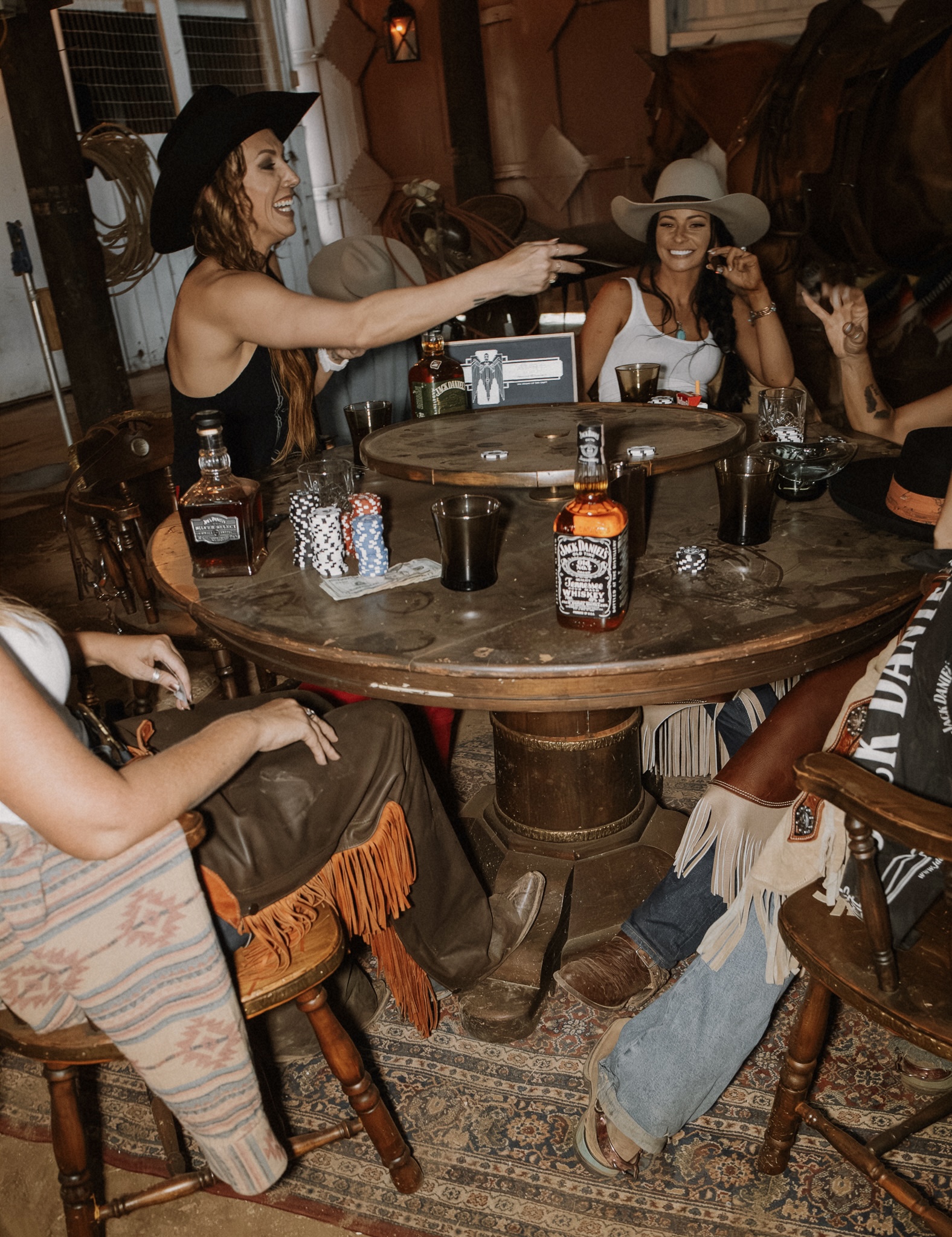 Cowgirls playing poker with Jack Daniel's at barn table