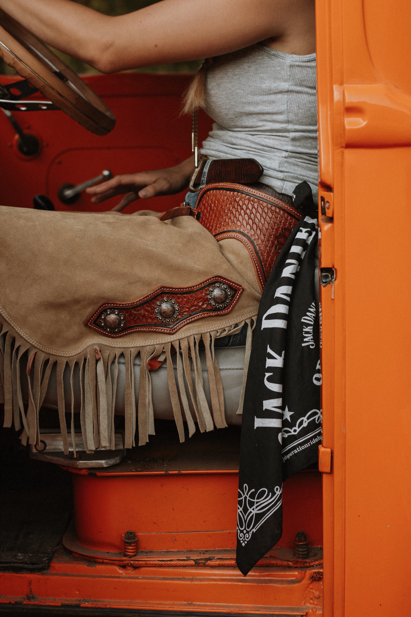 Cowgirl in vintage orange truck with Jack Daniel's bandana