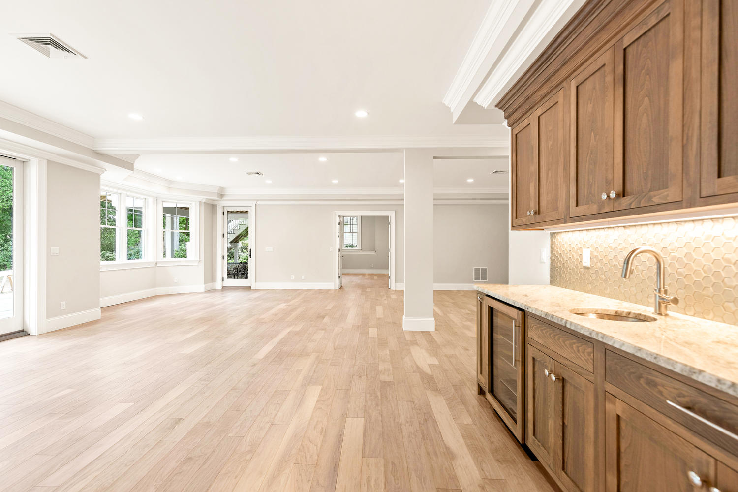 Lower level wet bar with walnut cabinetry, hexagonal tile backsplash, and beverage refrigerator