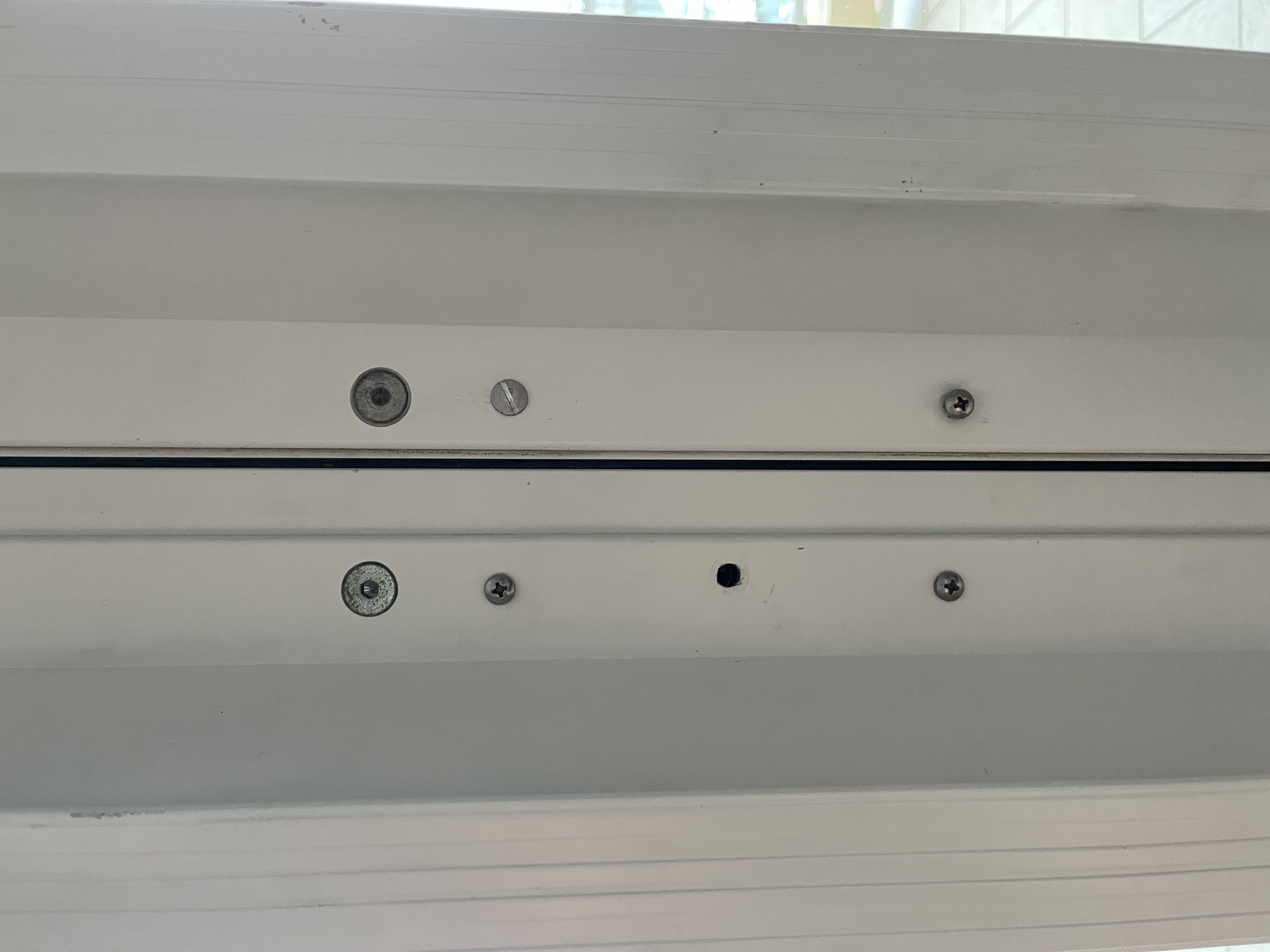 Before: balcony sliding door frame with no secondary lock, only exposed screw holes