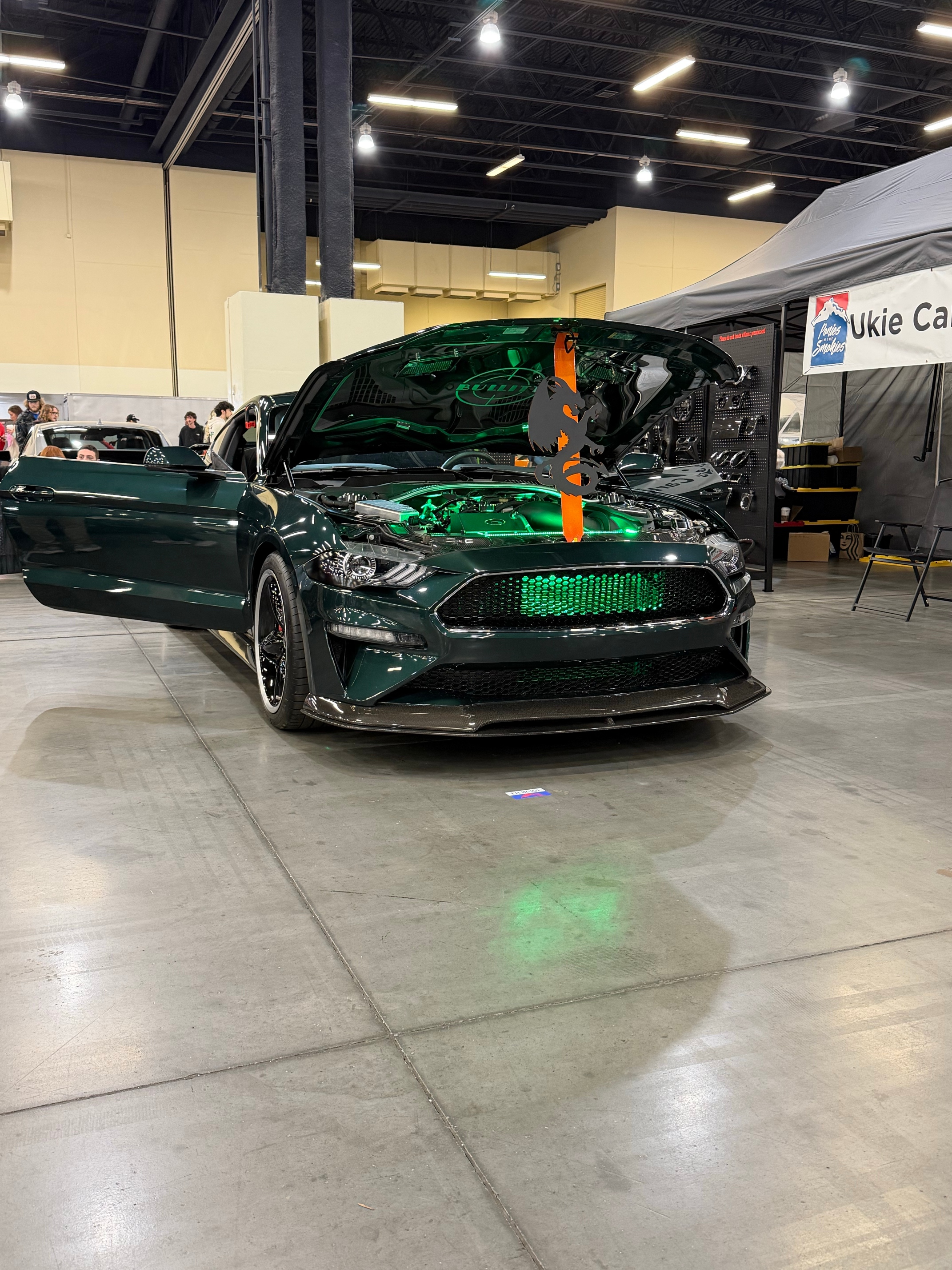 Ford Mustang Bullitt with hood open showing green-lit engine bay at an Oklahoma car show