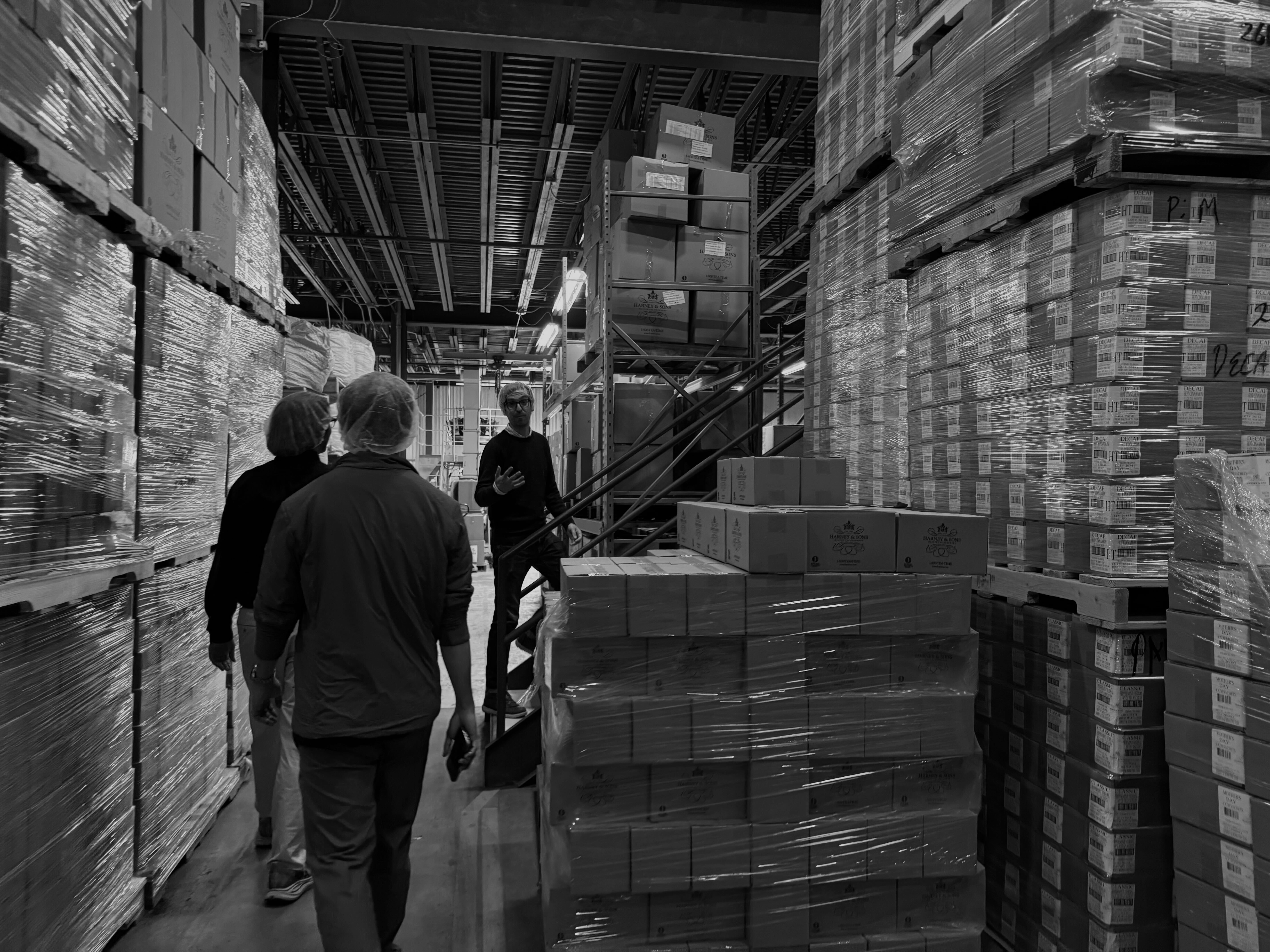 Warehouse tour with workers among stacked pallets