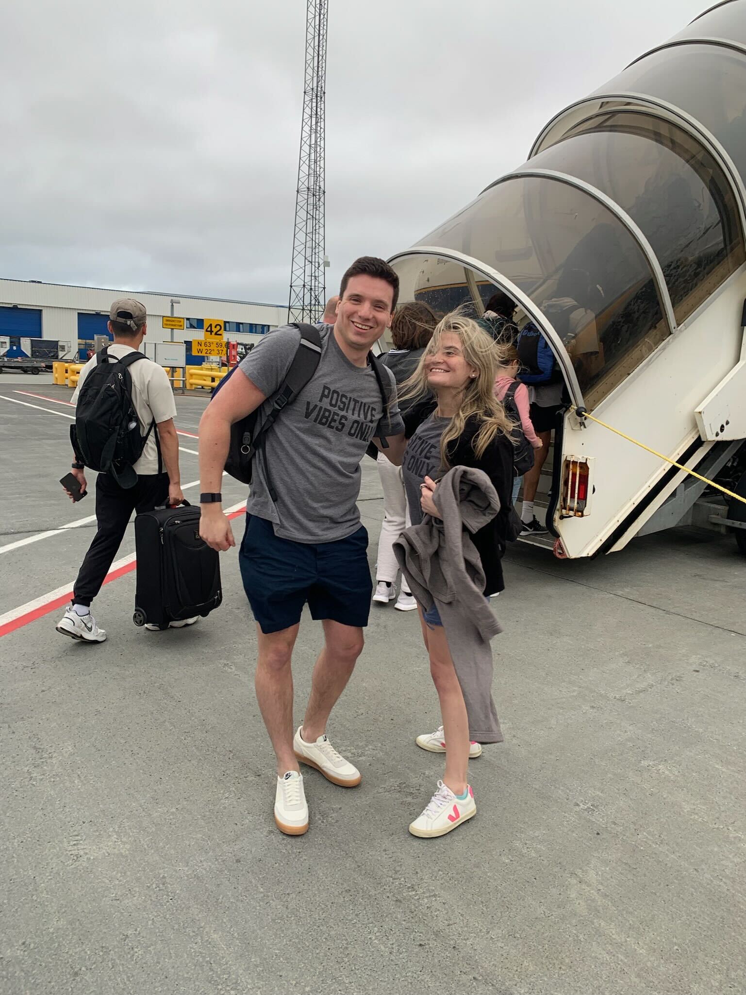 Ben and Brooke at the airport wearing matching Positive Vibes Only t-shirts, ready for another adventure