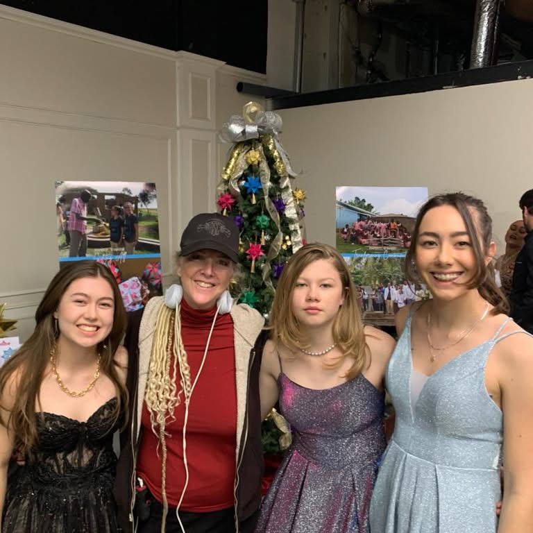 Paper for Water volunteers posing with the director in front of a decorated Christmas tree on the Gingersnap Christmas set