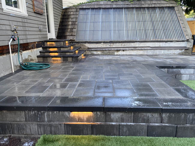 Wet-finish charcoal paver patio with integrated lighting