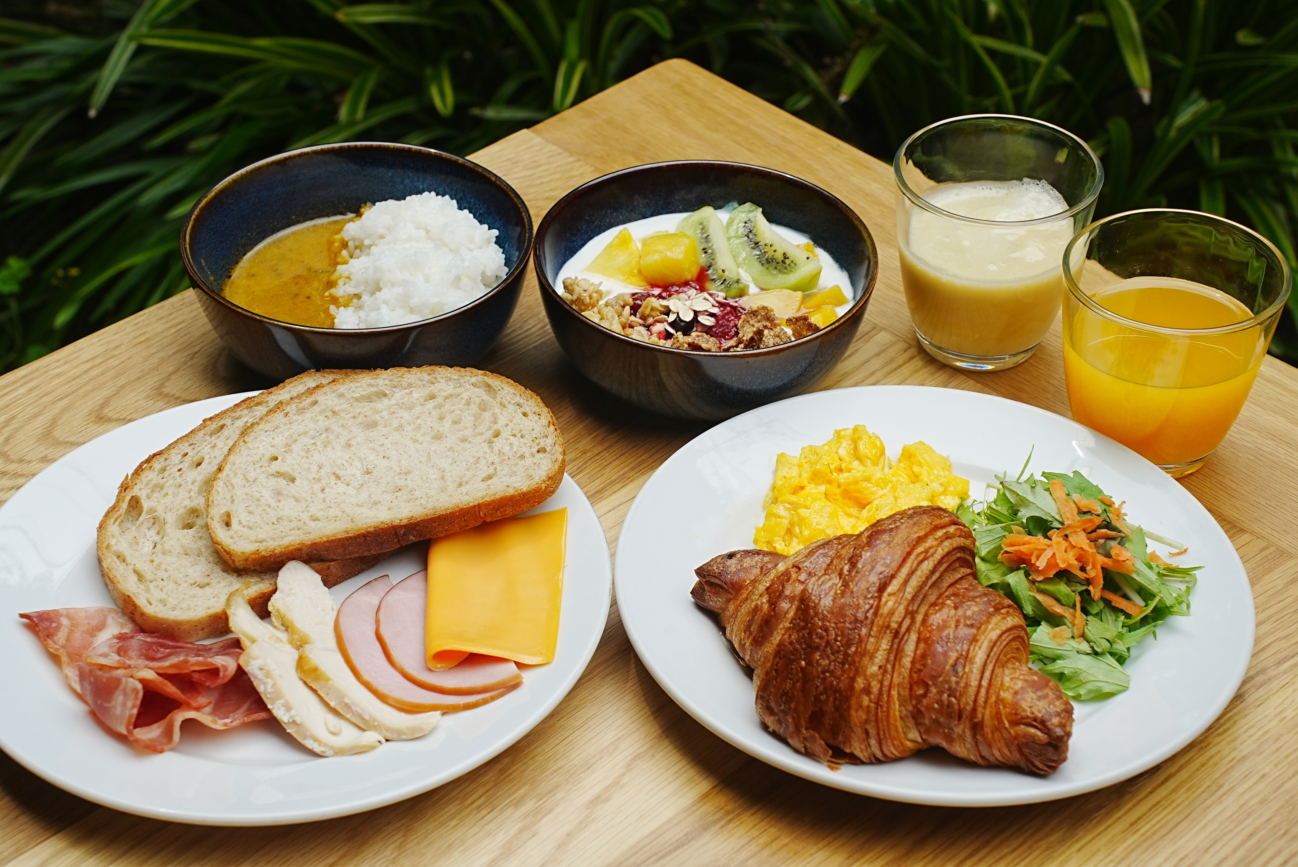 Kyoto breakfast plate with Shinshindo bread, croissant, salad, curry rice, smoothie, and fresh fruit