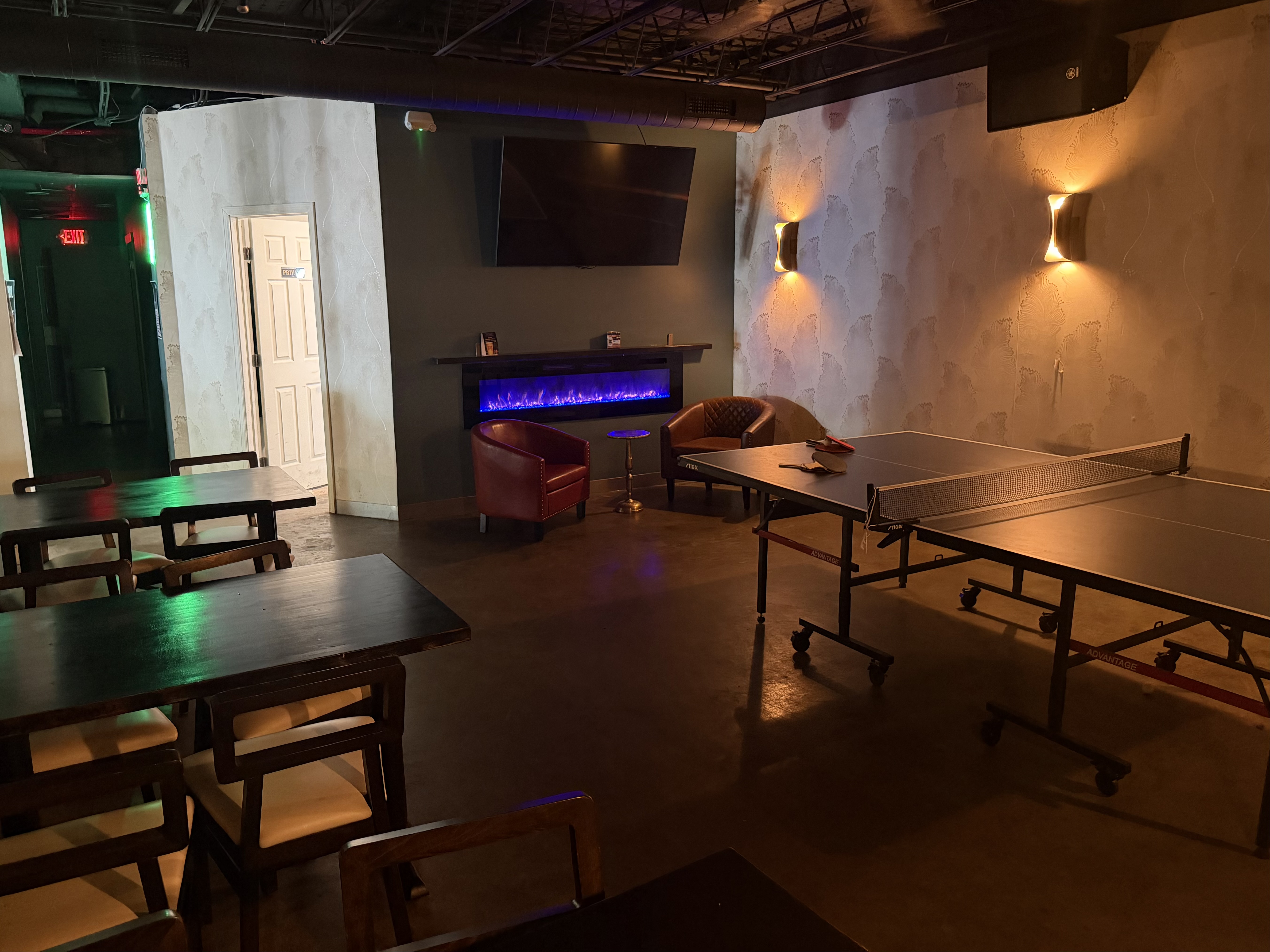 Private event room with ping pong table, electric fireplace, and lounge seating