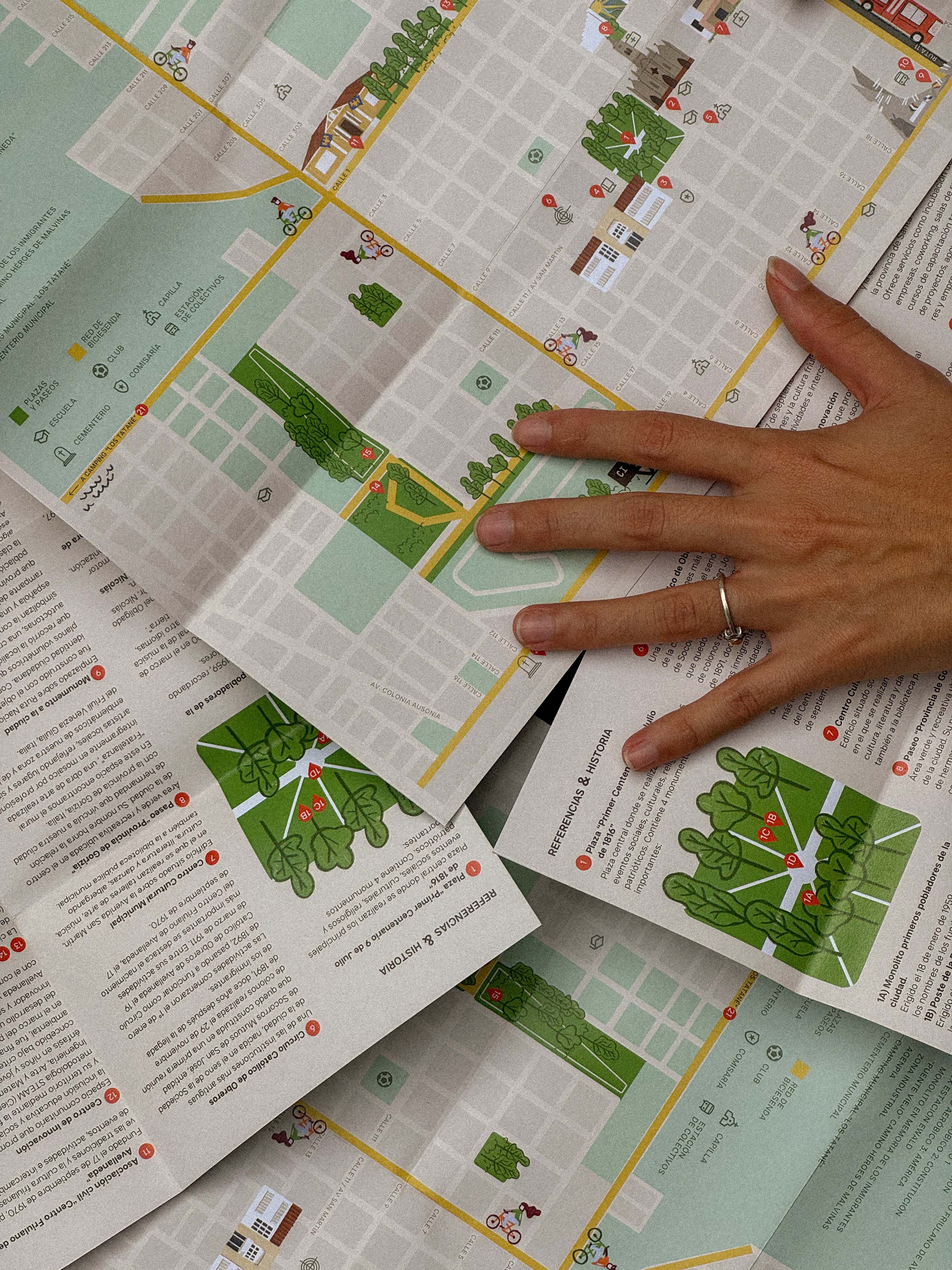 Mapa turístico Avellaneda - Mano sobre varios mapas desplegados