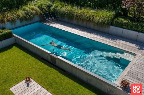 Aerial view of person swimming in a long in-ground container pool with wooden deck