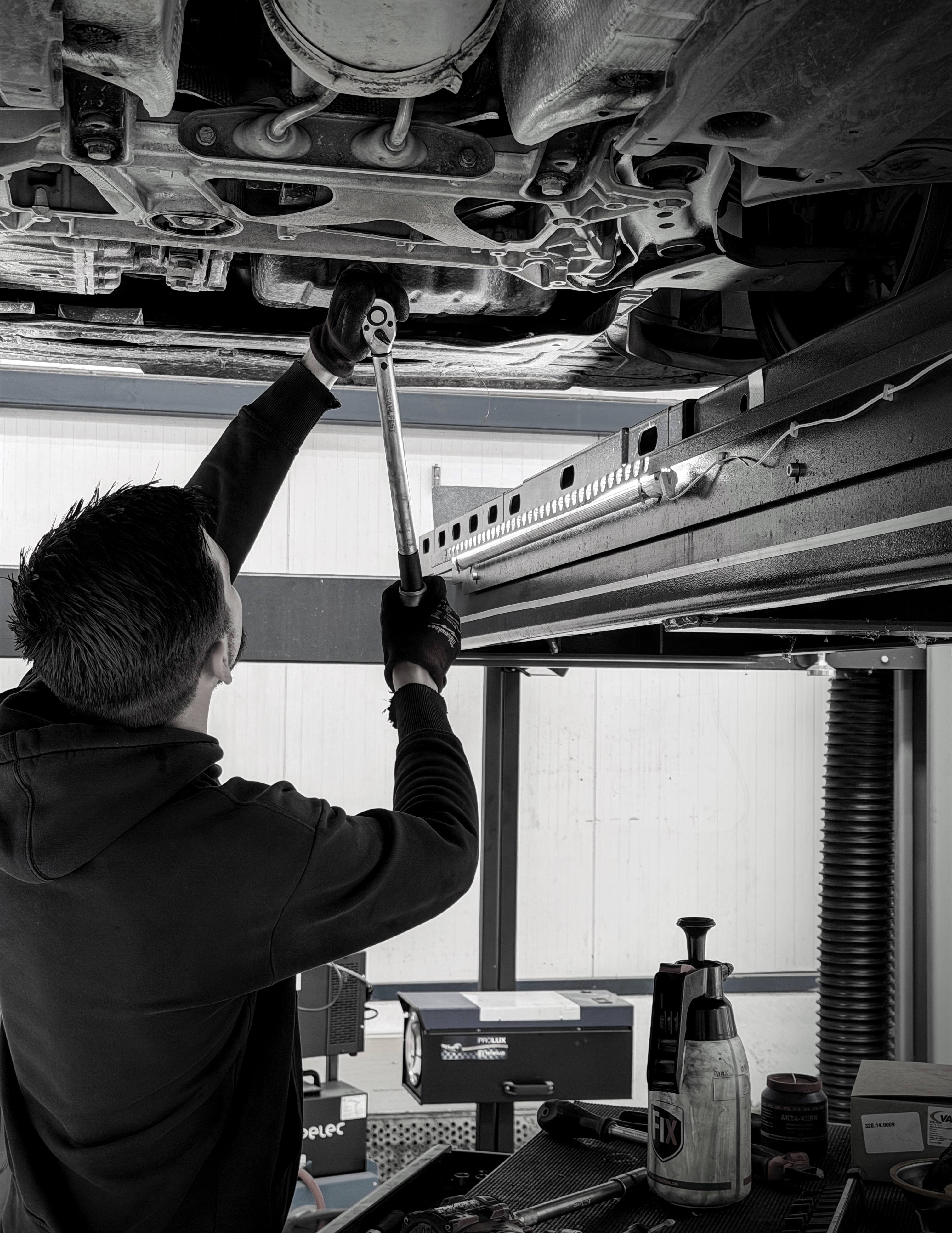 Monteur werkt met momentsleutel onder een opgeheven Volkswagen