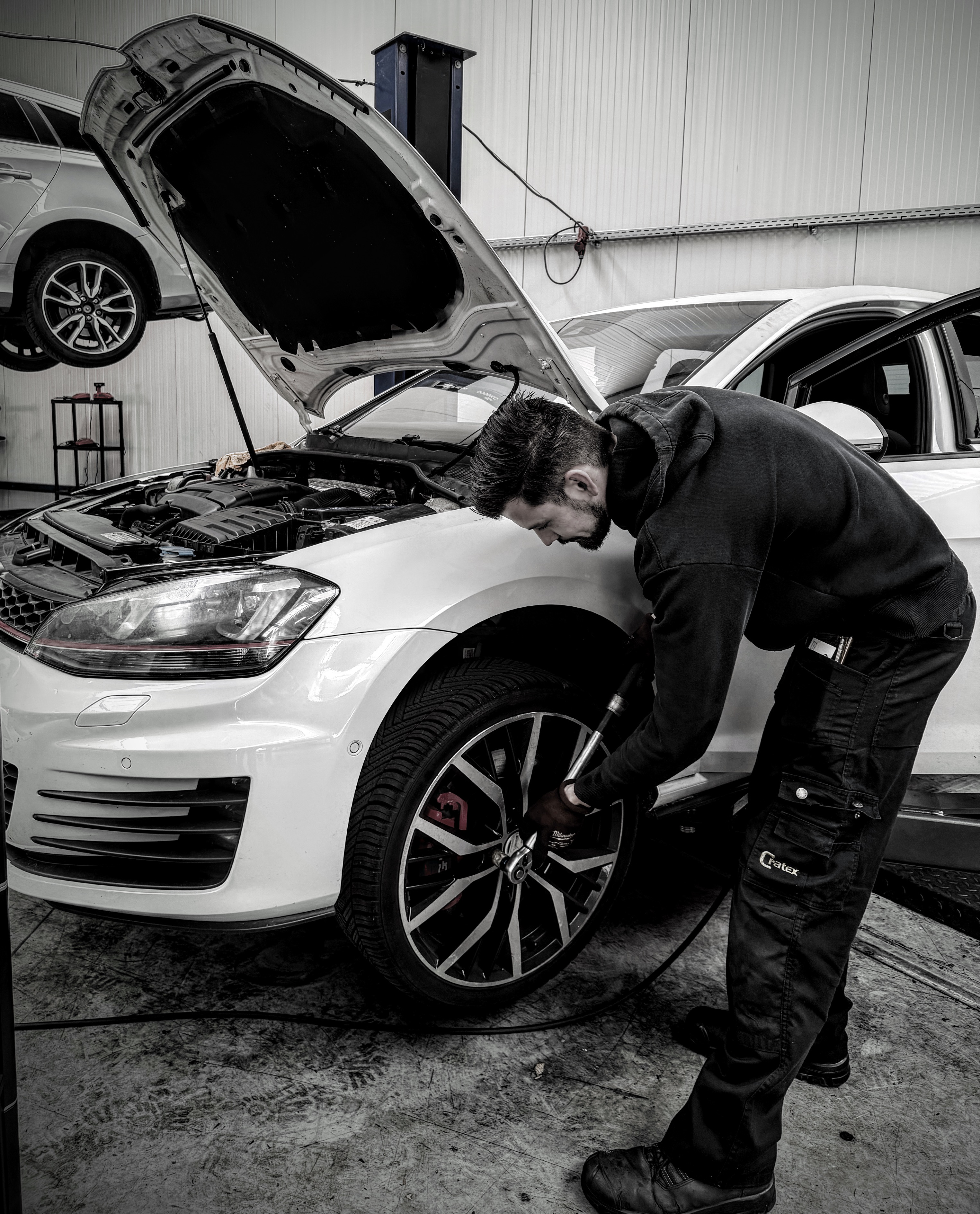 Monteur monteert een wiel op een witte Volkswagen Golf GTI