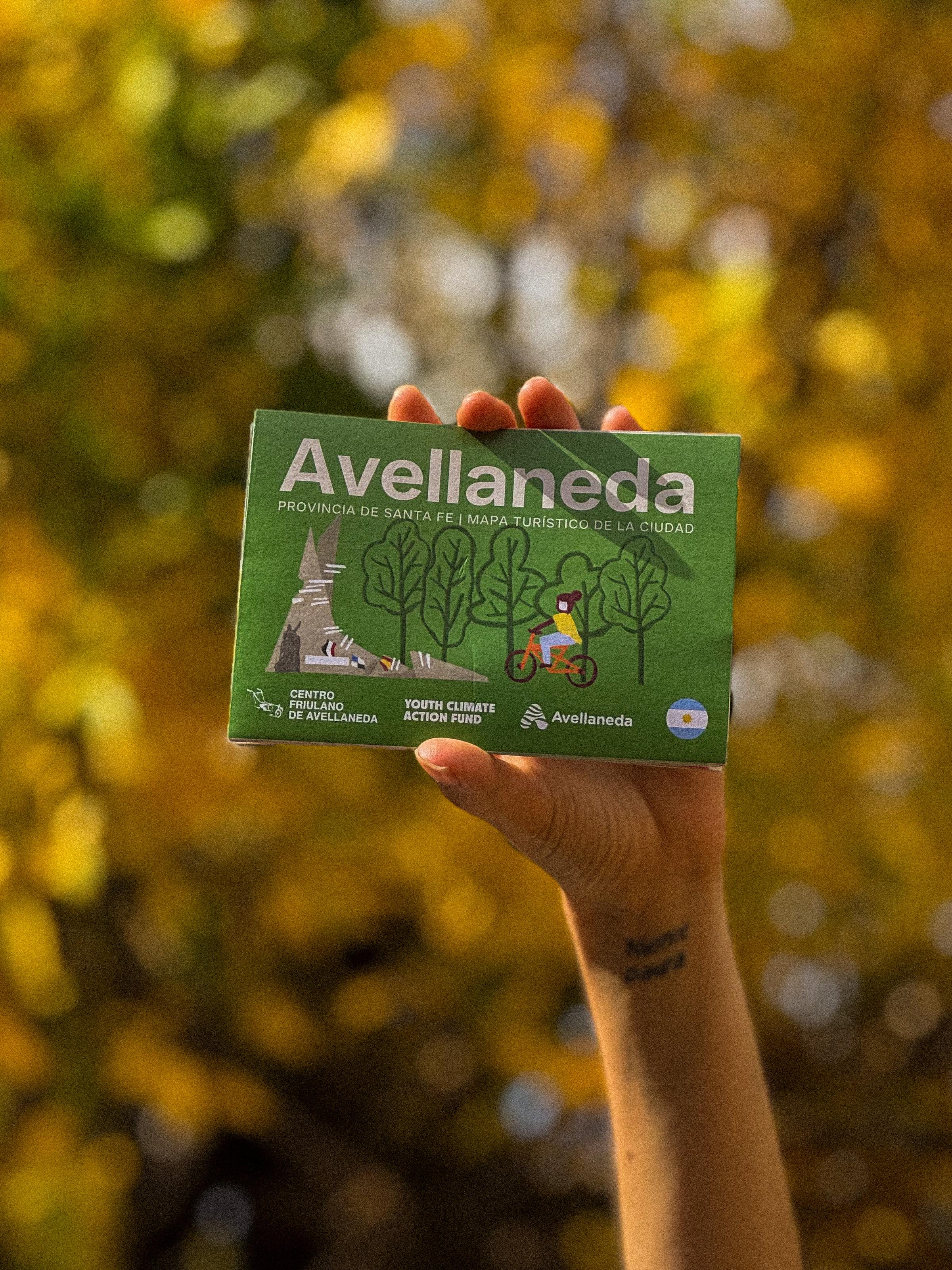 Mapa turístico Avellaneda - Folleto en mano con fondo otoñal