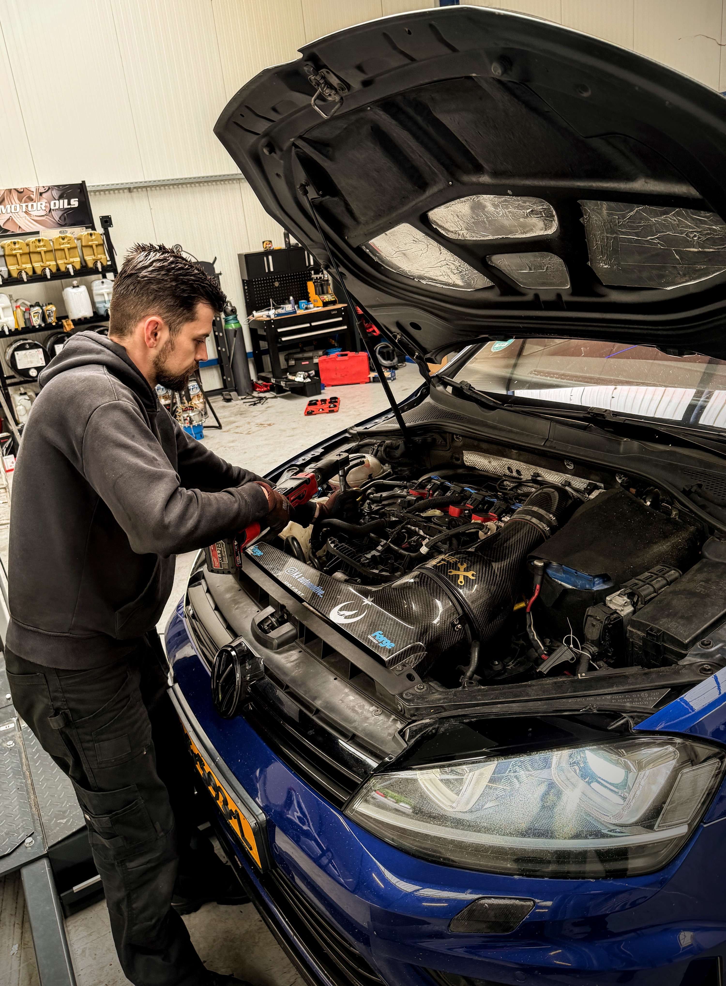 Monteur werkt aan de motorruimte van een blauwe Volkswagen