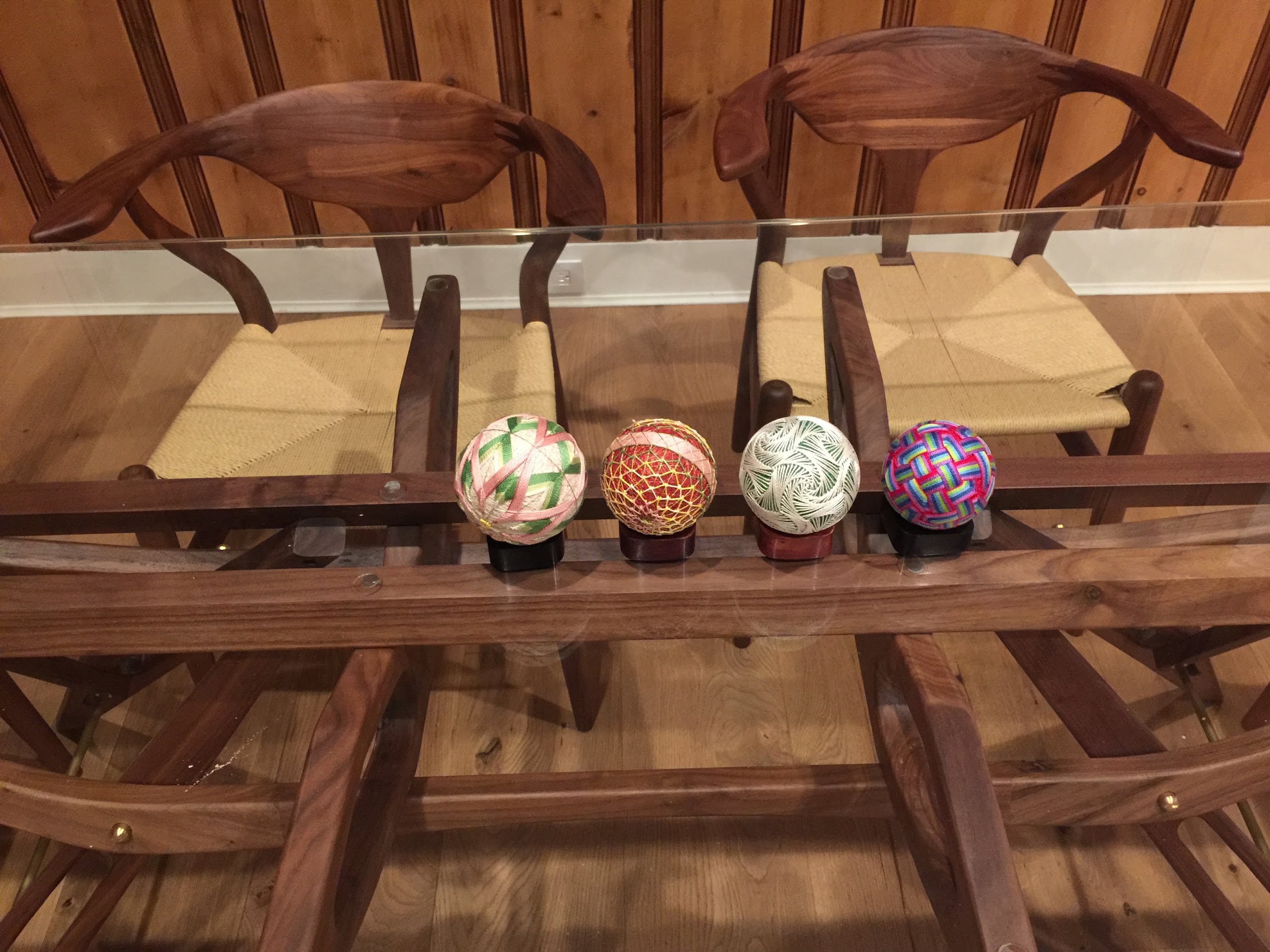 Four handstitched Japanese temari balls on wooden stands, each with a distinct woven pattern