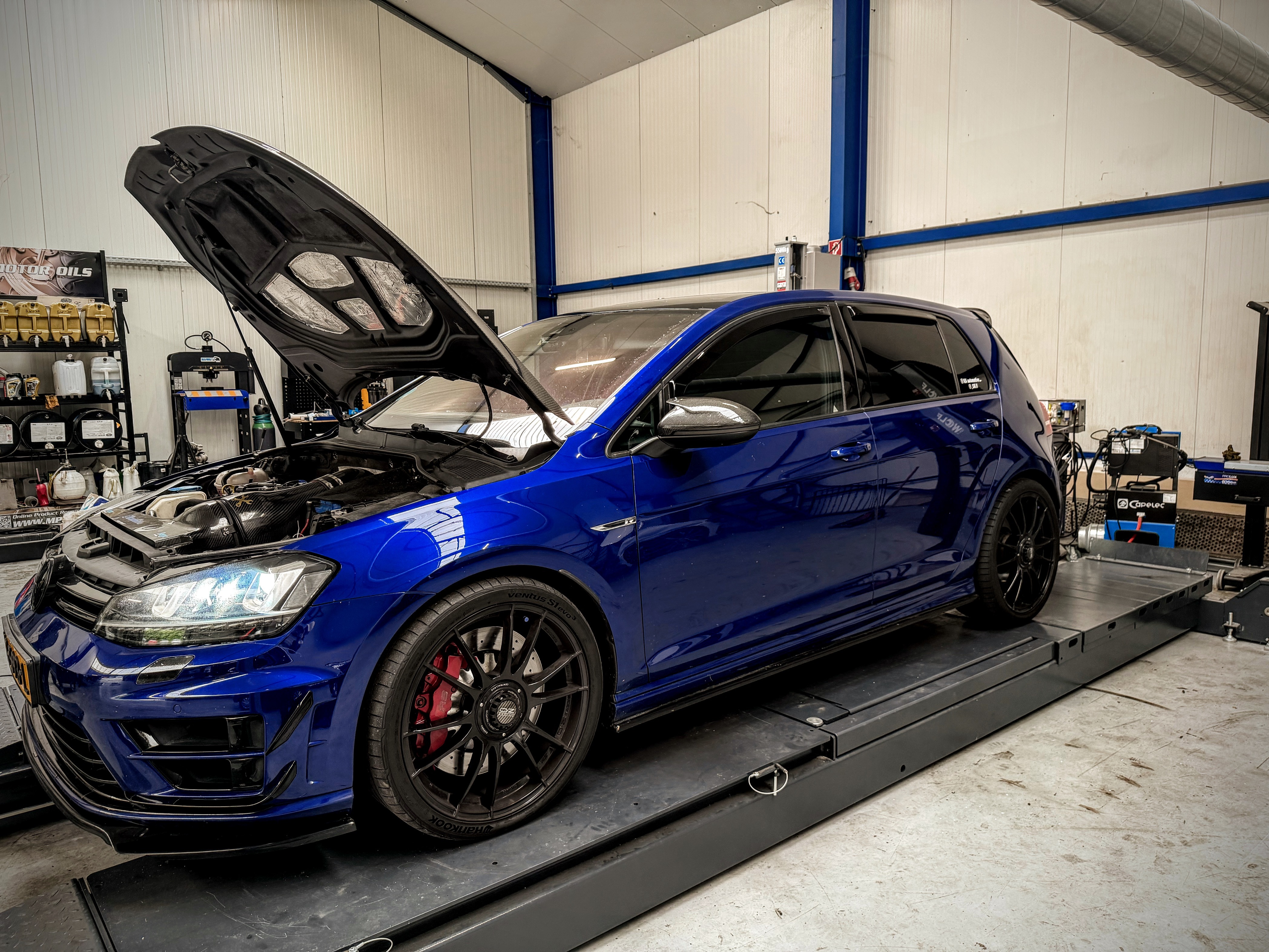 Blauwe Volkswagen Golf R met geopende motorkap op de testbank