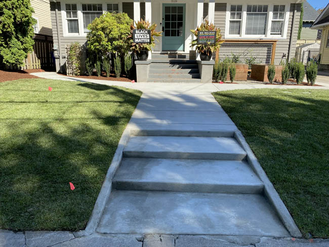 Fresh concrete walkway with stepped grade leading to bungalow