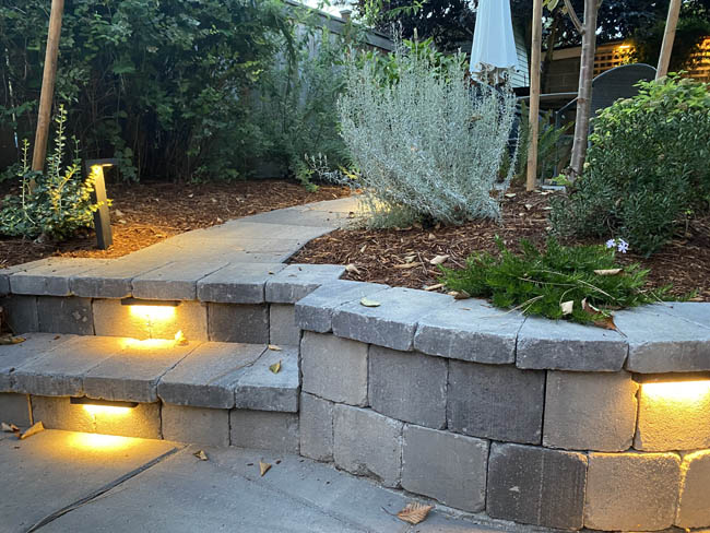 Stacked stone retaining wall with steps and integrated step lighting