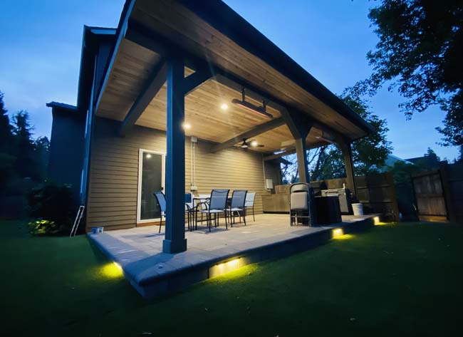Timber post-and-beam patio cover with integrated lighting at dusk