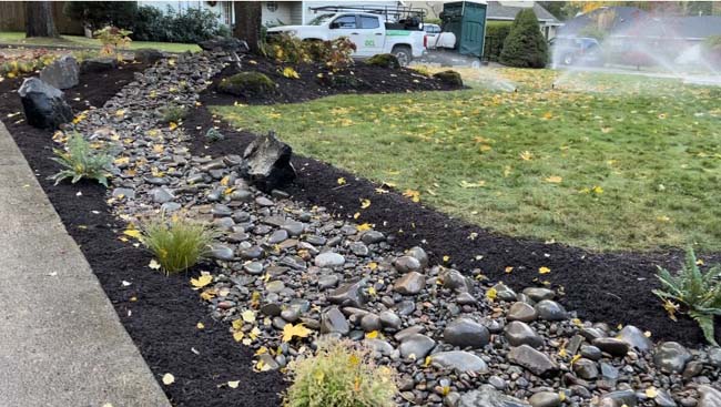 Autumn dry creek bed with river rock, ornamental grasses, and mulch beds