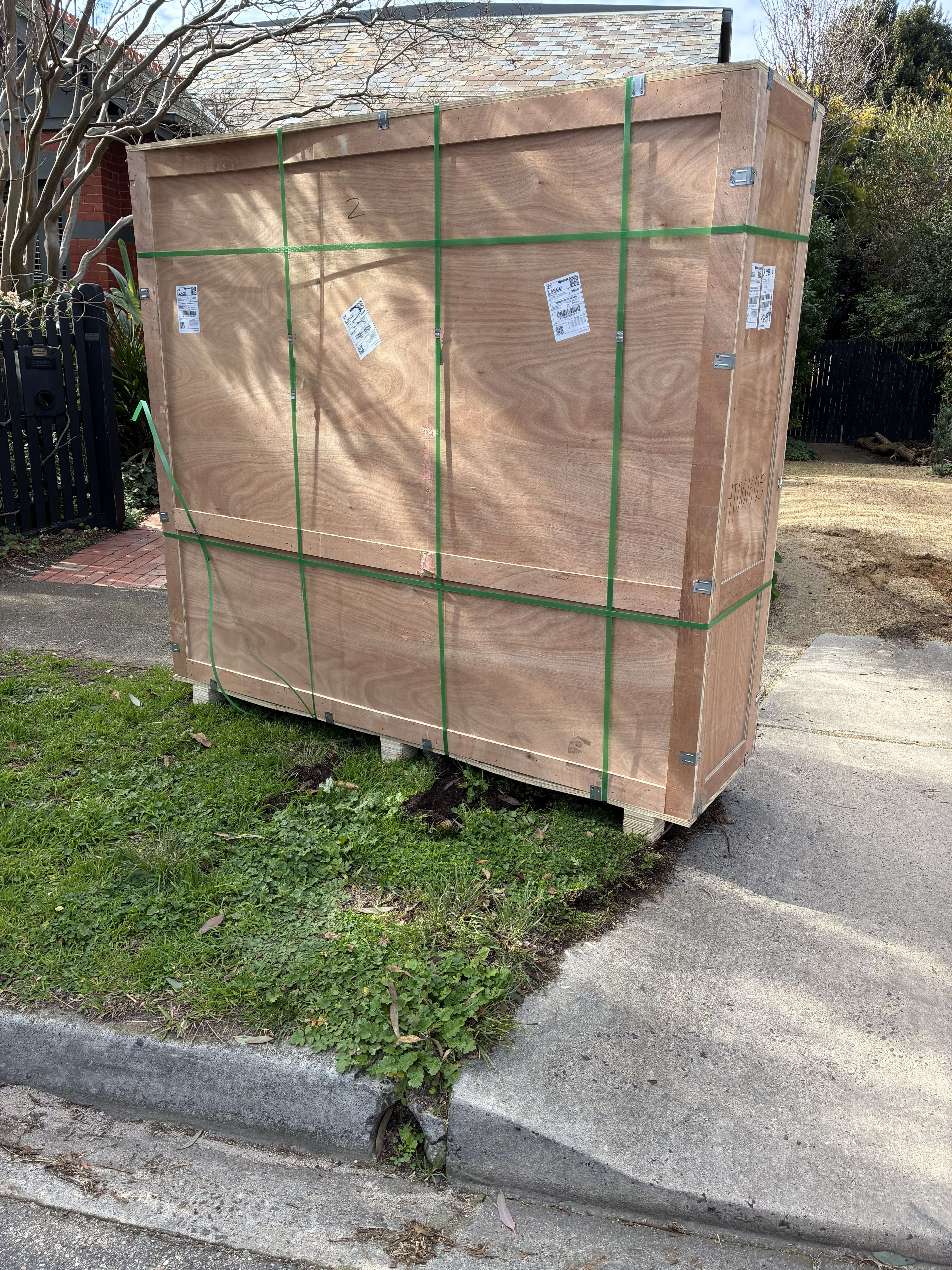 The green-strapped plywood shipping crate safely delivered and resting on site, ready for installation