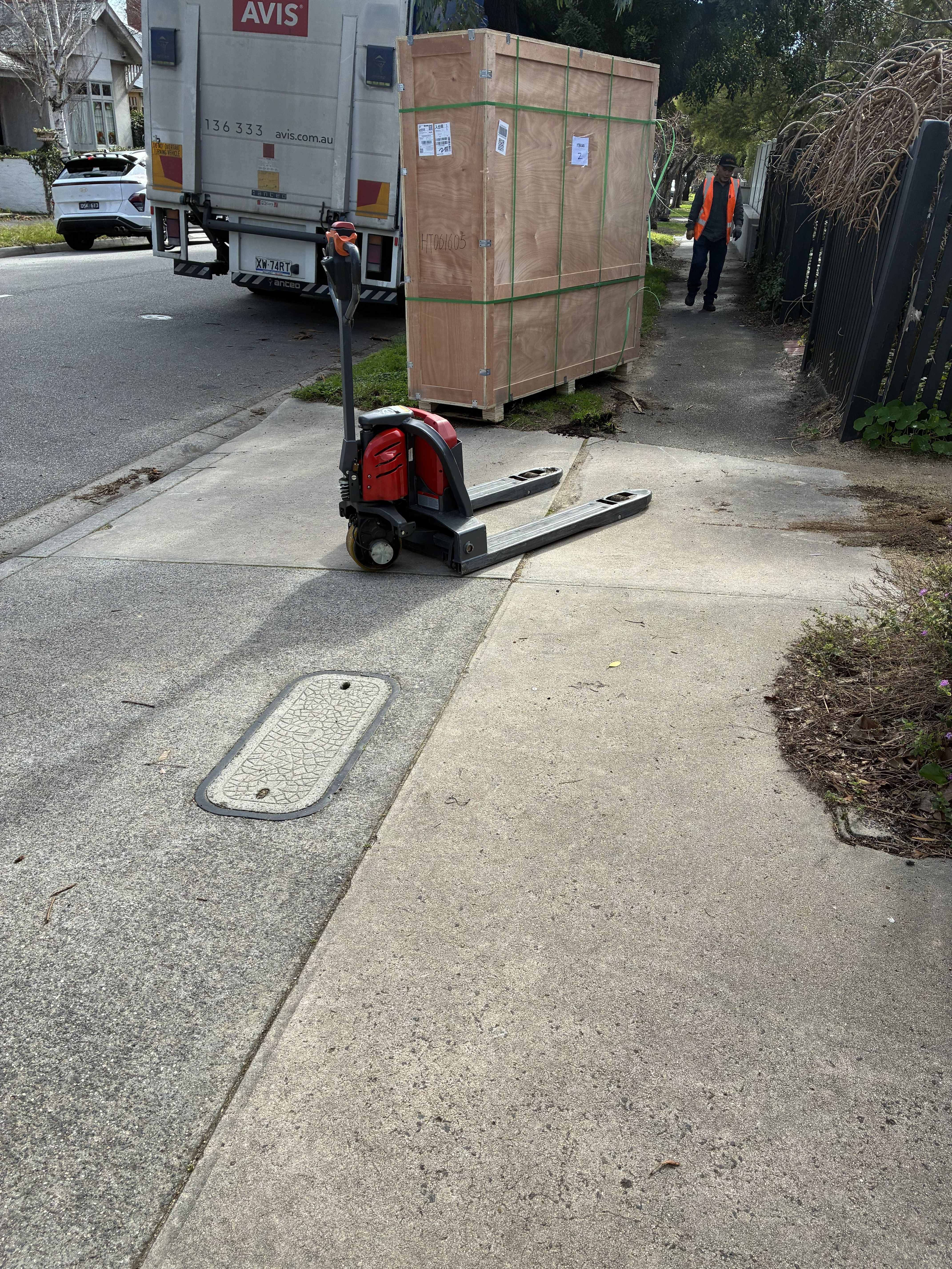 The crated Prahran sauna being unloaded from the delivery truck and moved along the footpath on an electric pallet jack