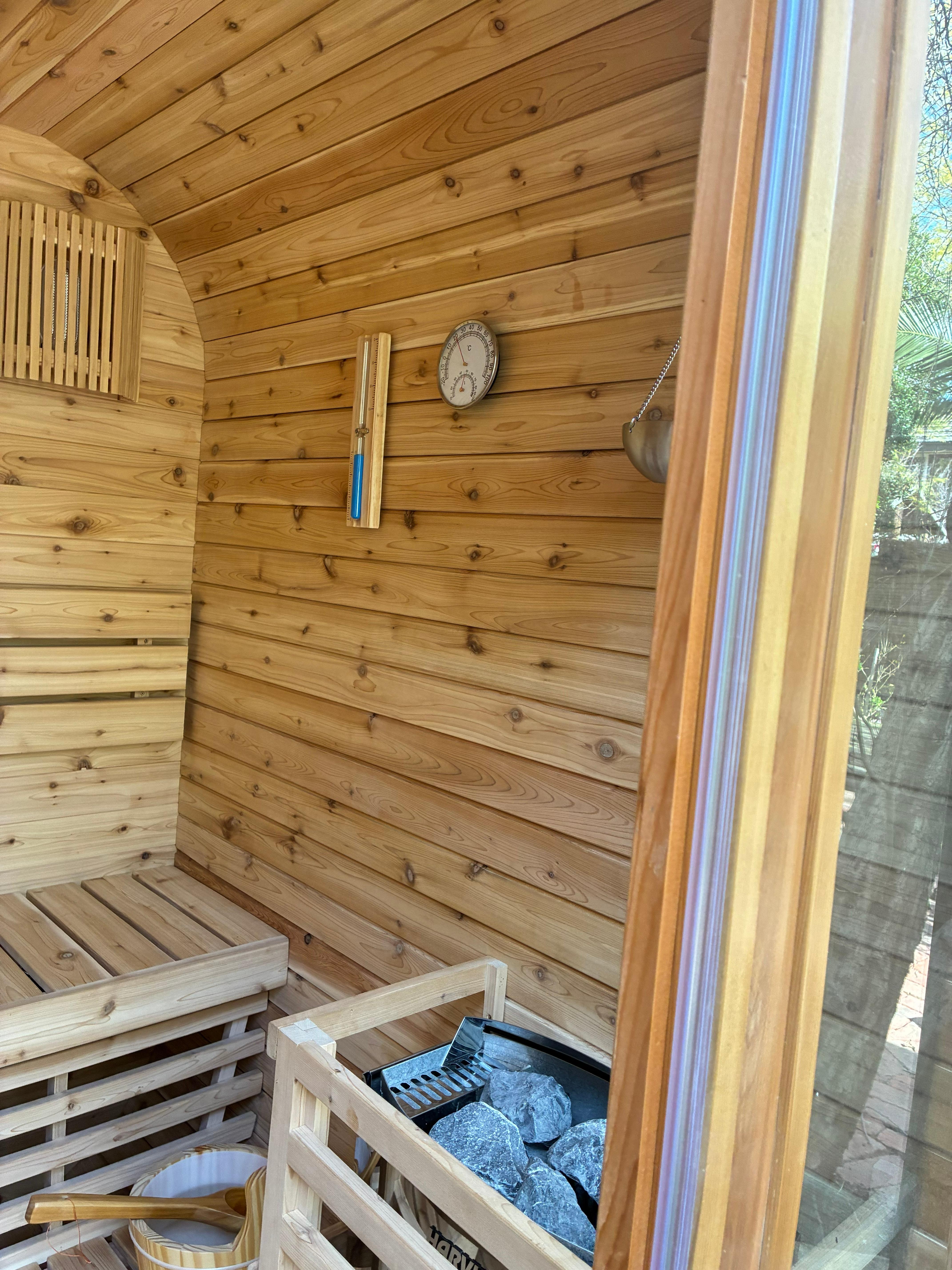 Finished cedar interior with a wall thermometer, sand timer and the rock-topped Harvia heater