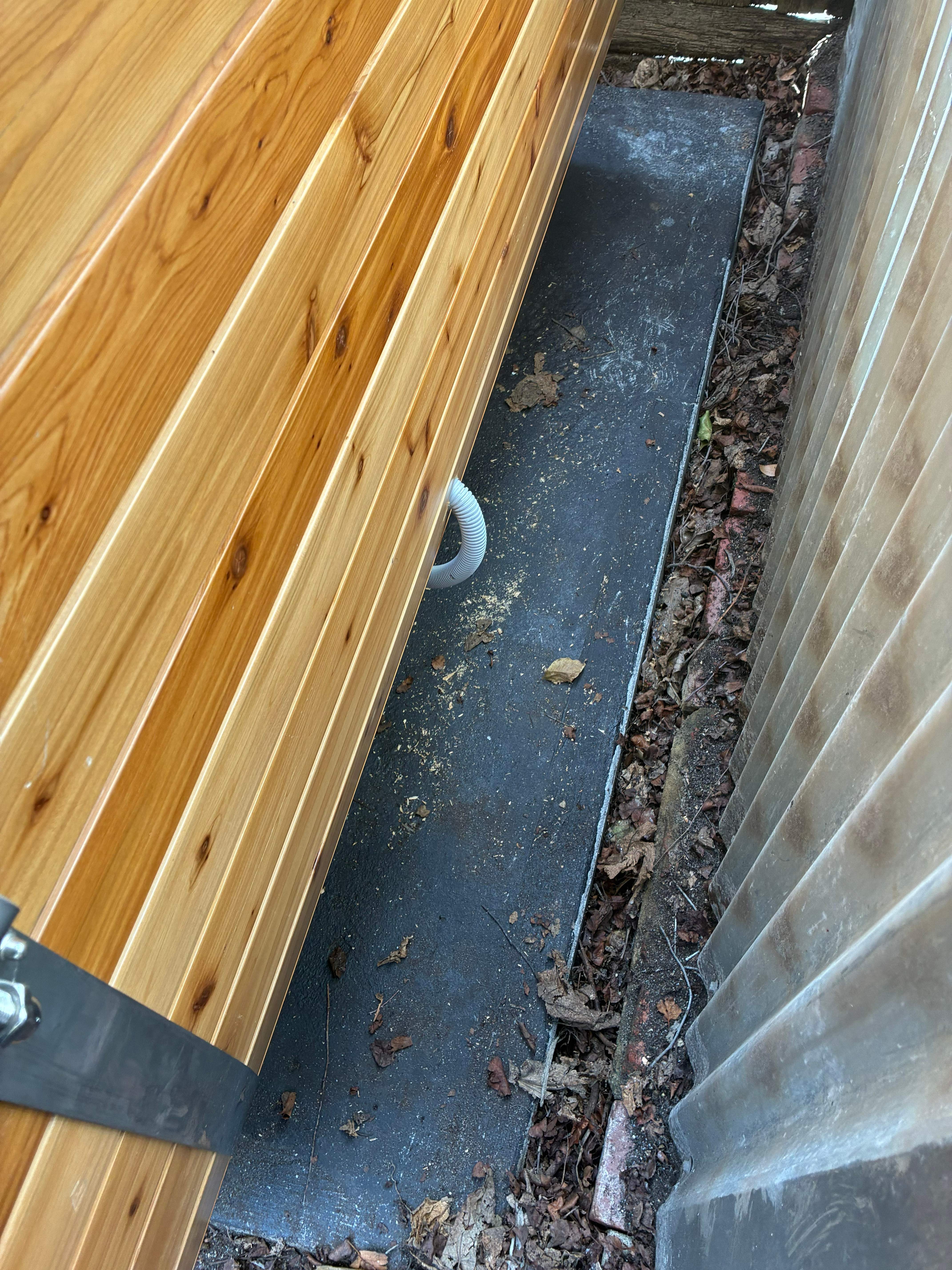 Cedar sauna set on its levelled base during installation, with power conduit run to the unit