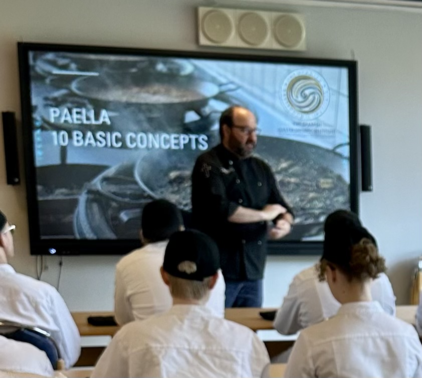 Carlos Ripoll demostrando técnica de paella a alumnos en cocina profesional