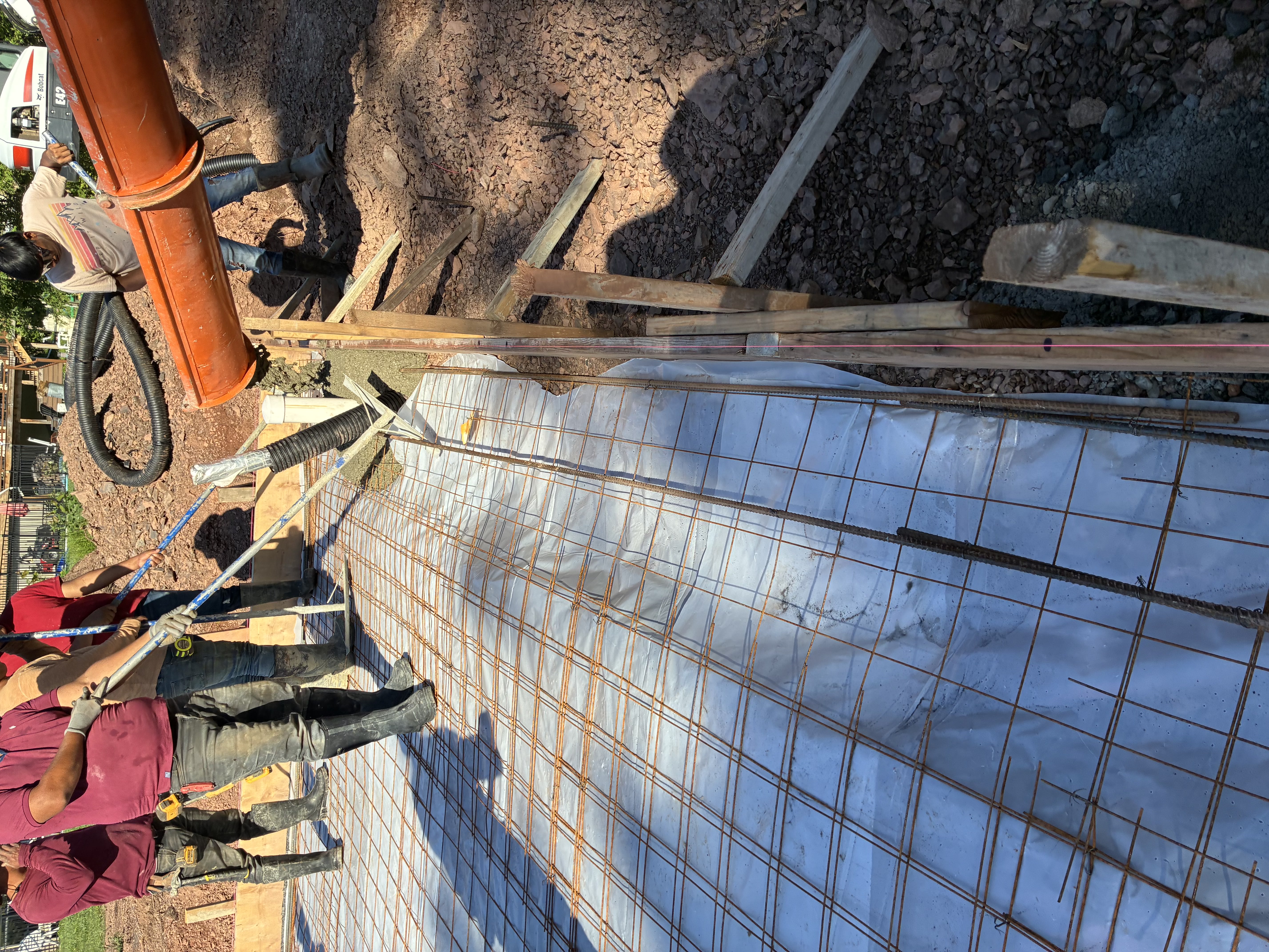 Multiple crew members pouring slab with pump truck