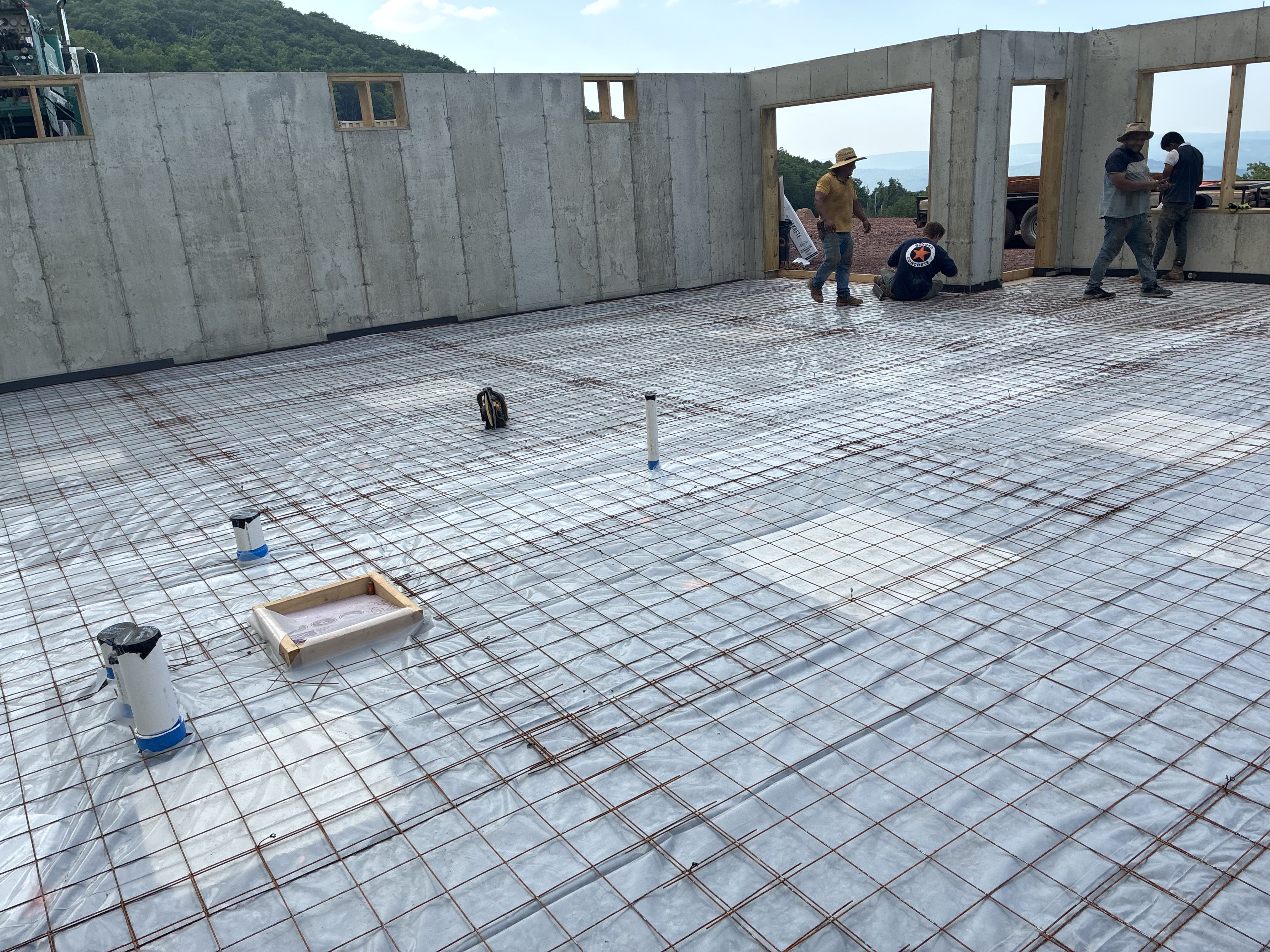 Crew working on large basement slab prep with mountain view
