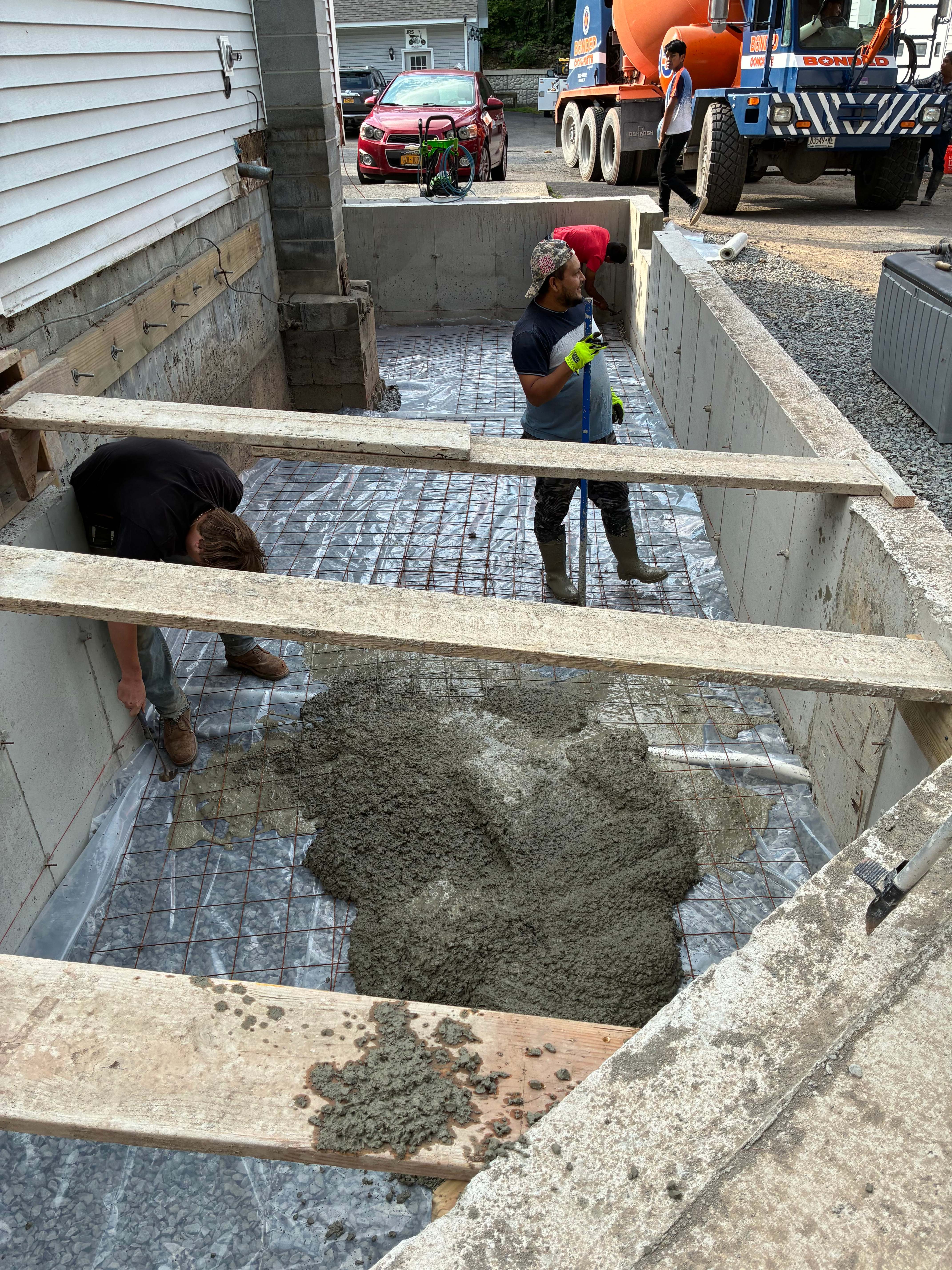 Crew pouring basement floor through chute