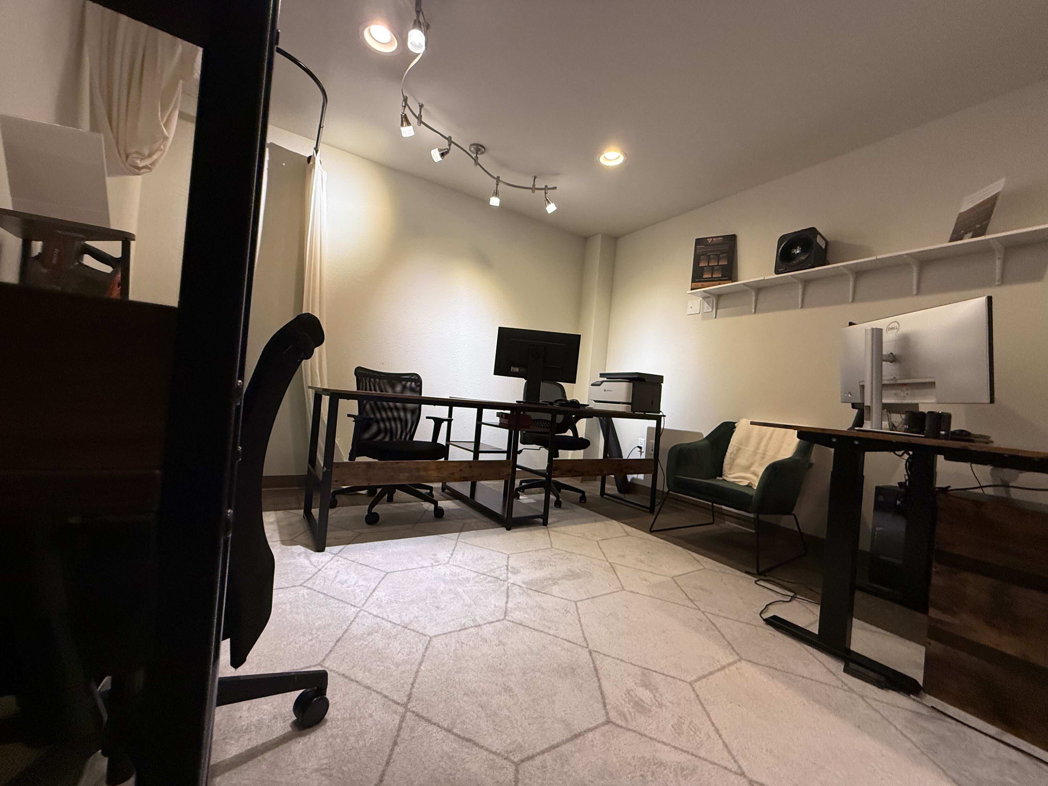 Wide view of coworking space with hexagonal tile flooring, multiple workstations and standing desks