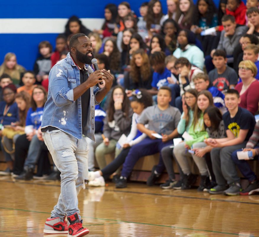 Andre Fluellen speaking to students in a gymnasium