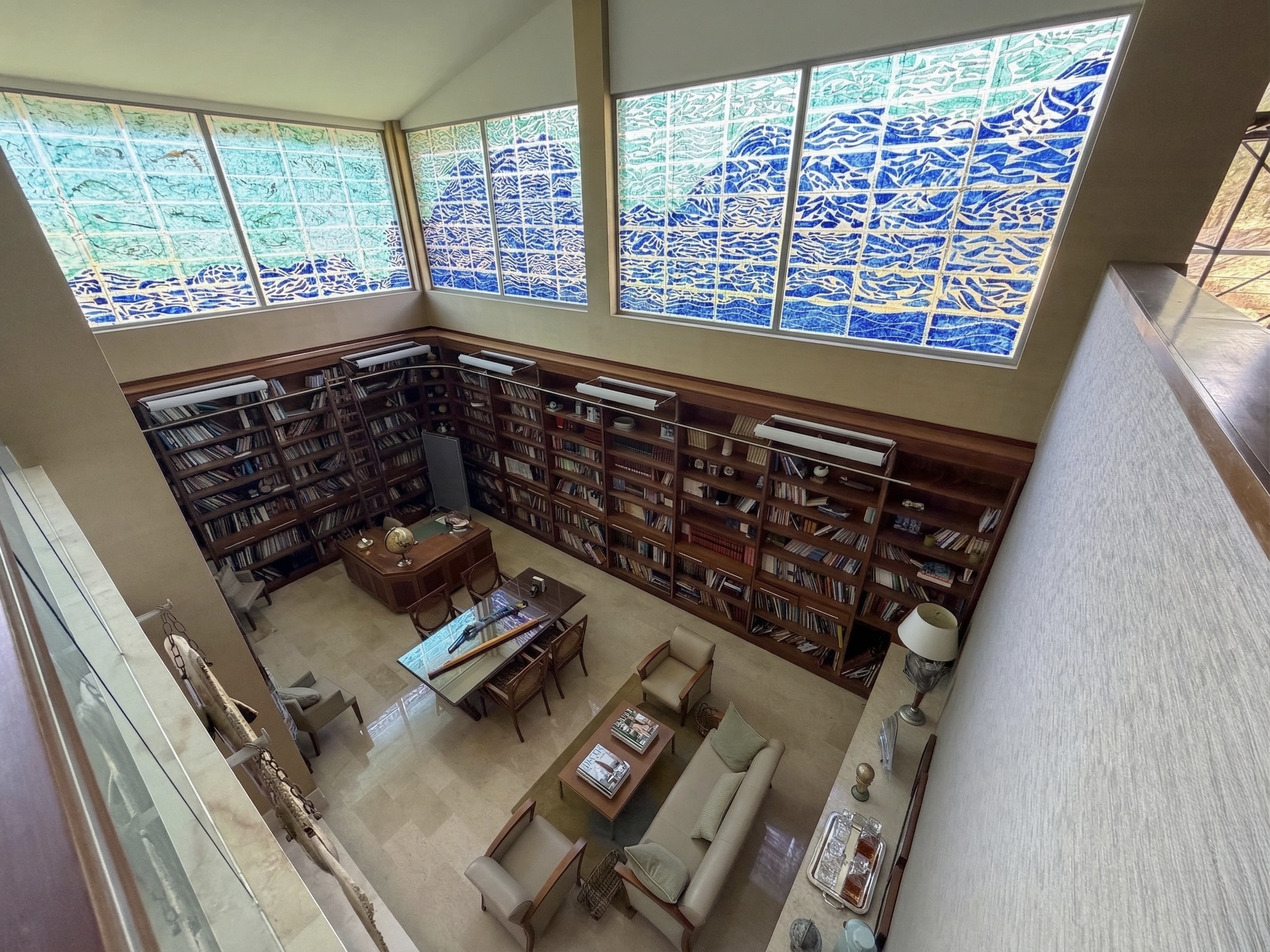 Private library with floor-to-ceiling mahogany bookshelves and stunning stained glass windows depicting ocean waves, La Trinidad estate