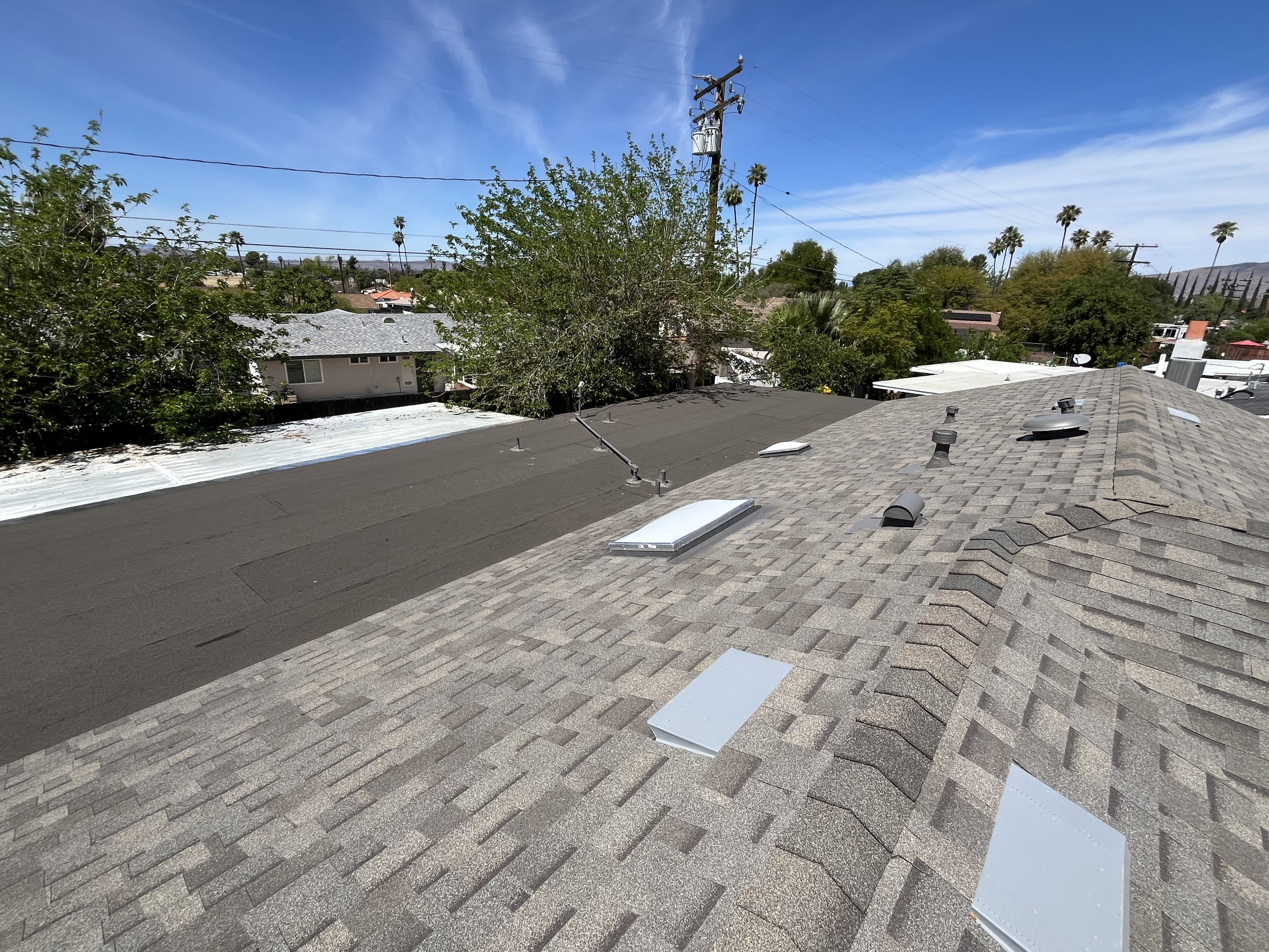 Completed shingle and torch-down flat roof system with skylights and roof vents