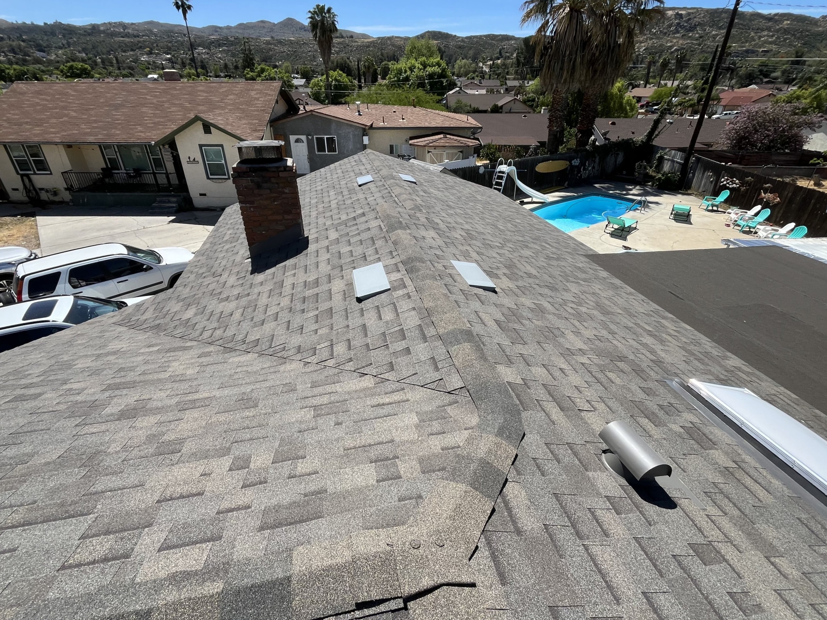 Completed tile roof installation with chimney and backyard pool view