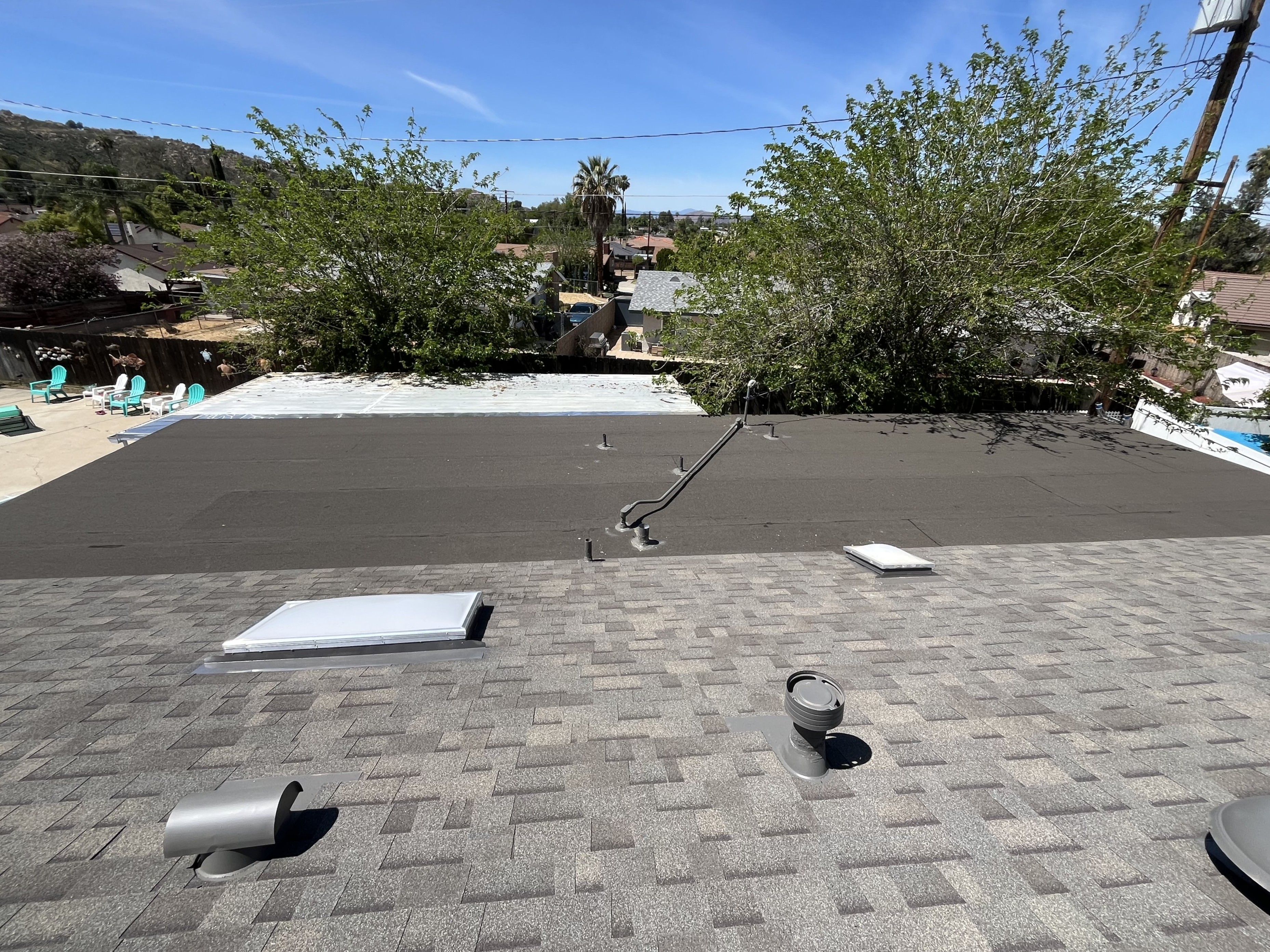 Torch-down flat roof detail next to shingle roofing