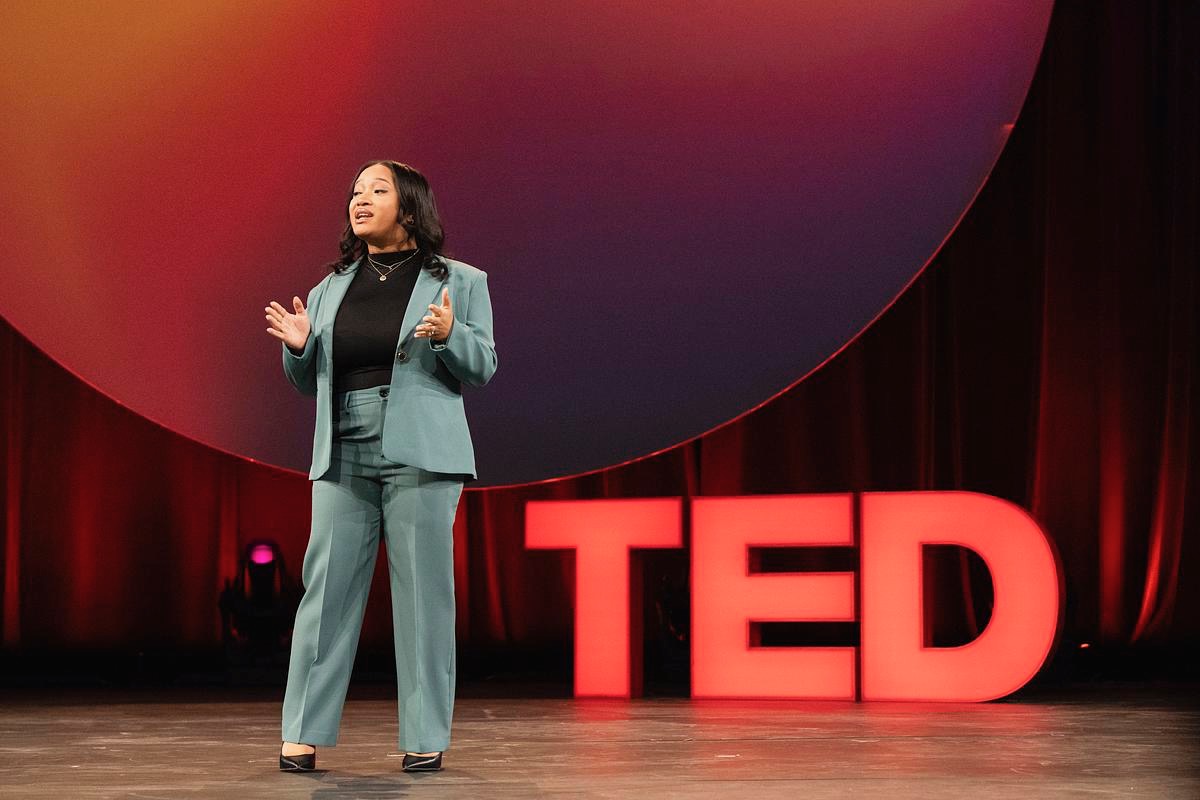 Steph Anya speaking on the TED stage, hands open