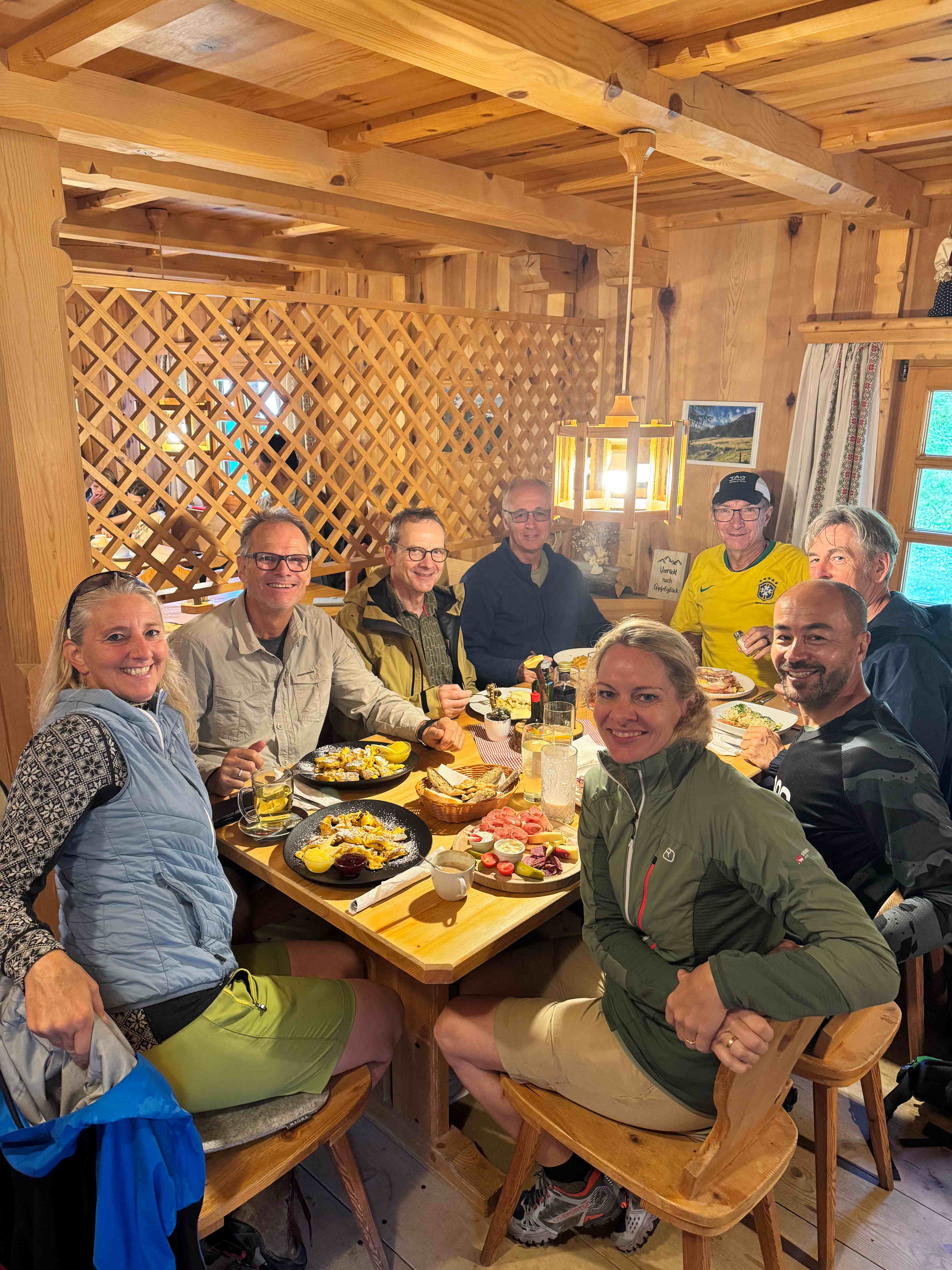 Gruppe beim gemeinsamen Essen in einer holzvertäfelten Hütte