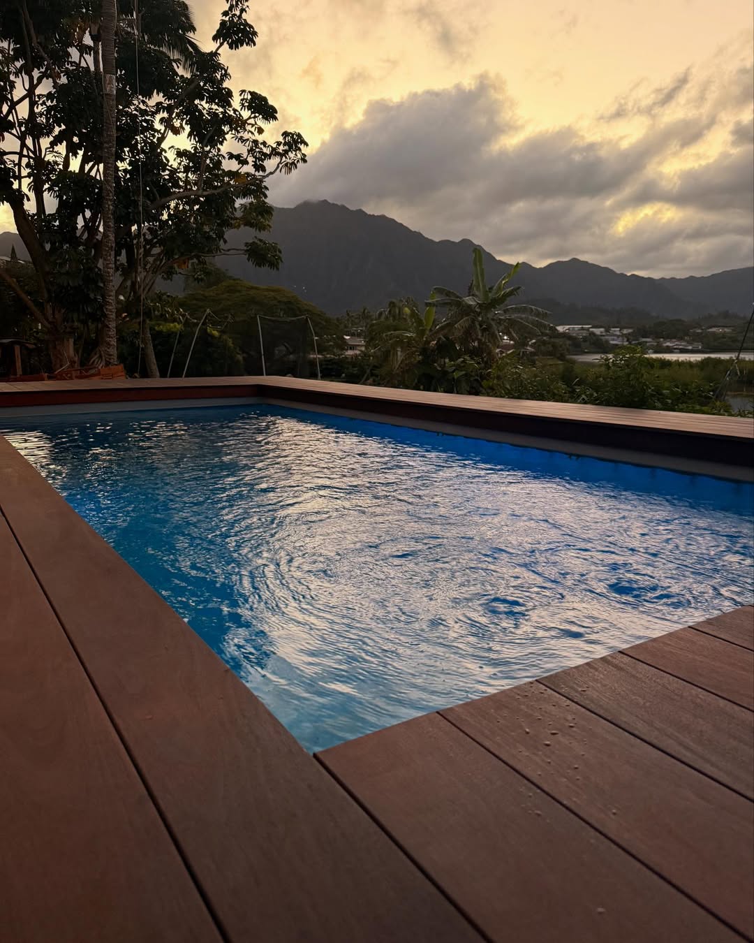 Container pool with wooden deck overlooking mountains at dusk