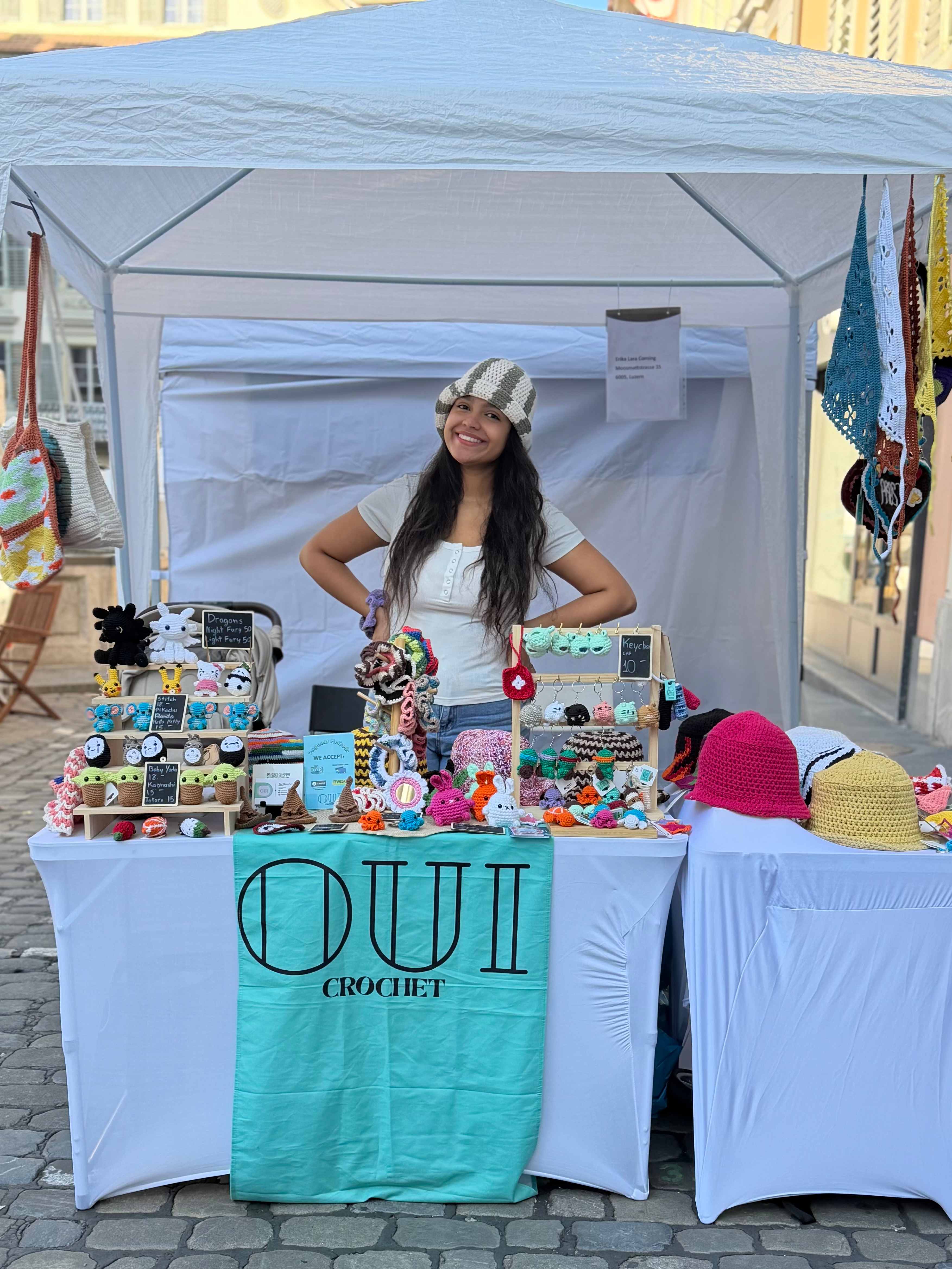 Erika at her OUI Crochet market booth surrounded by colorful handmade crochet creations