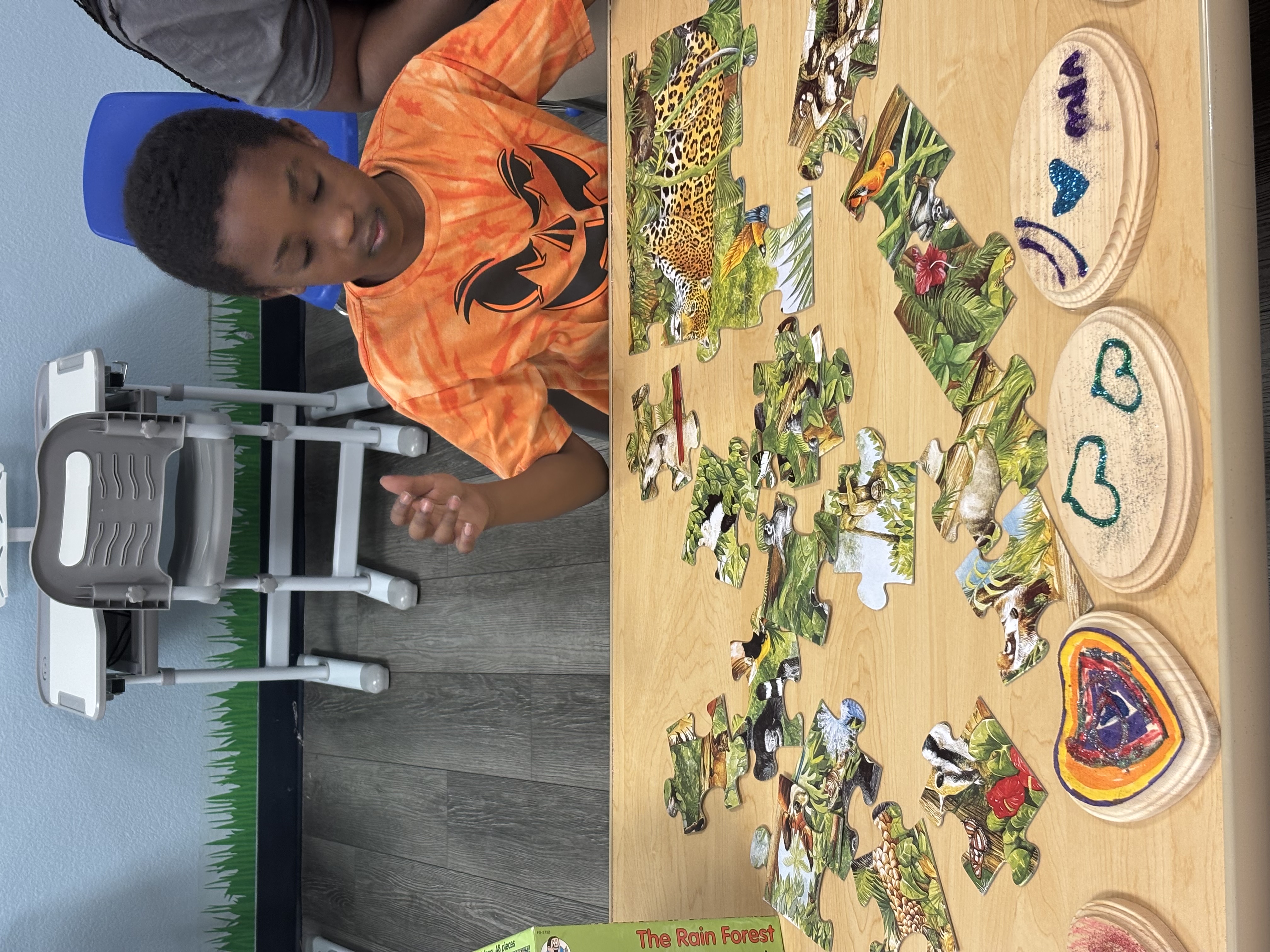 Student engaged in a colorful rainforest puzzle and cognitive crafting at a learning desk