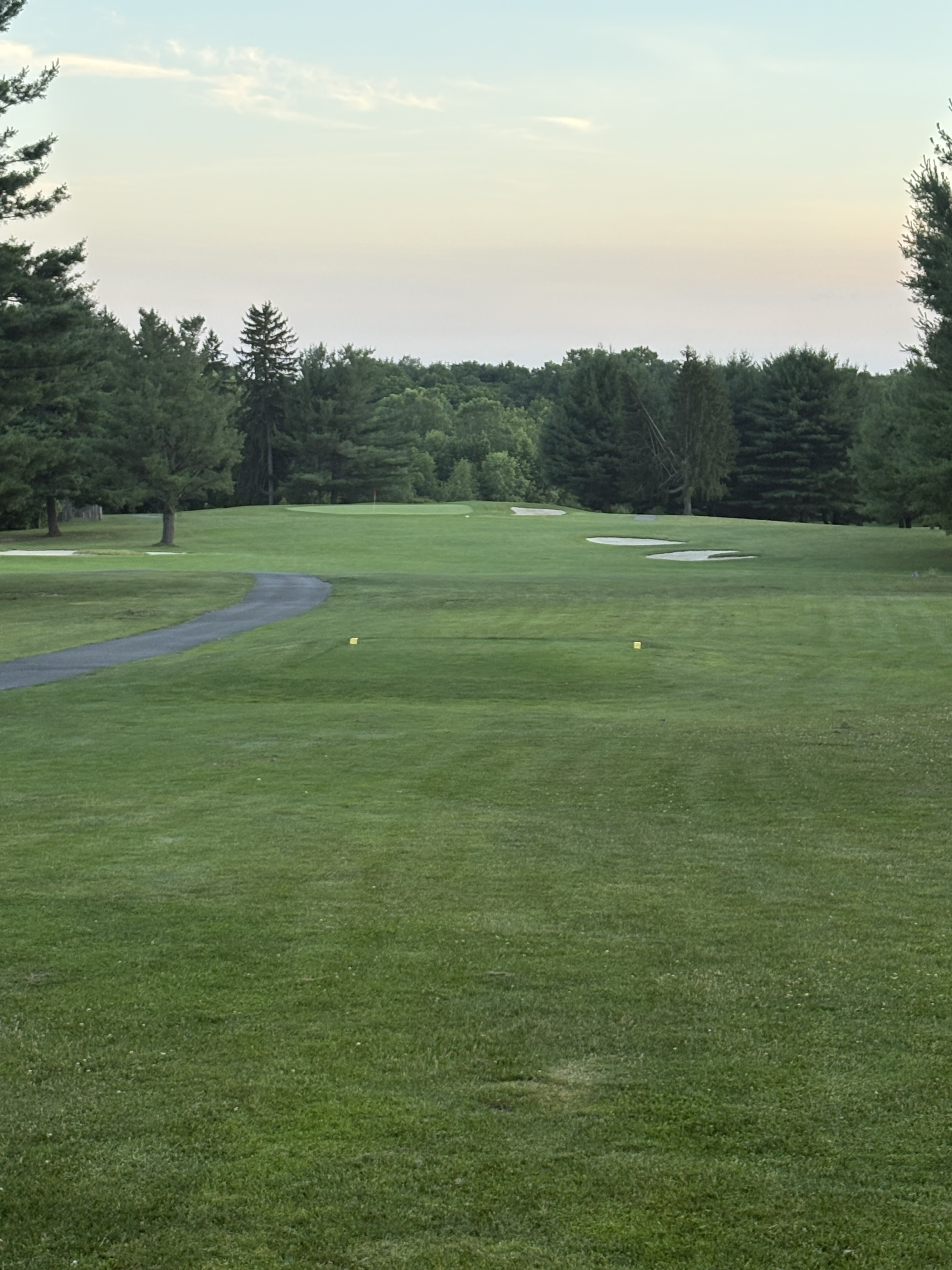 Fairway looking toward a green guarded by multiple sand bunkers at dusk